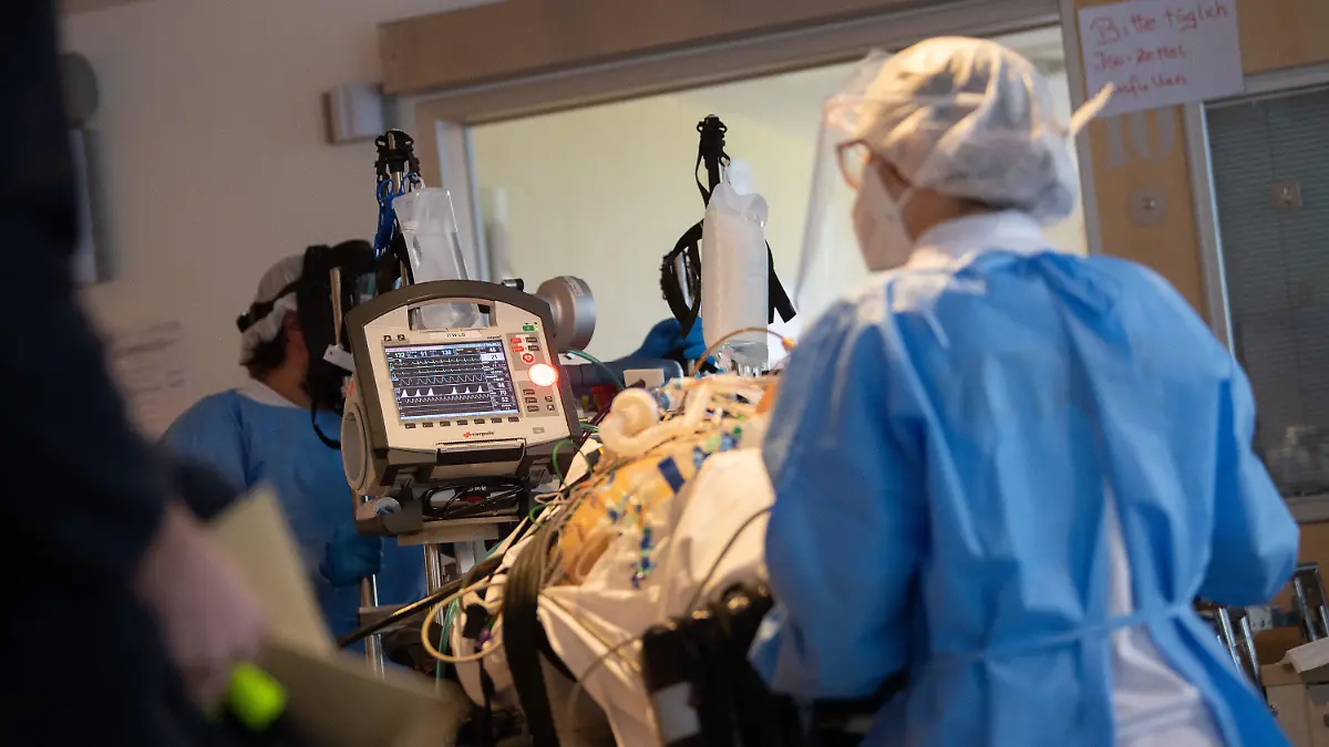 08.01.2021, Baden-Württemberg, Ludwigsburg: Das Team eines Intensivtransportwagens fährt auf einer Intensivstation des RKH Klinikum Ludwigsburg einen Covid-19-Patienten, der aus einem anderen Krankenhaus verlegt wurde, auf einer Intensivtrage. In Baden-Württemberg wird die Belegung der Intensivstationen mit einem Clusterkonzept gesteuert. Zwischen den Kliniken der sechs Versorgungsgebiete können Intensivpatienten verlegt werden, um eine bessere Verteilung zwischen den Krankenhäusern zu erreichen. Foto: Sebastian Gollnow/dpa +++ dpa-Bildfunk +++
