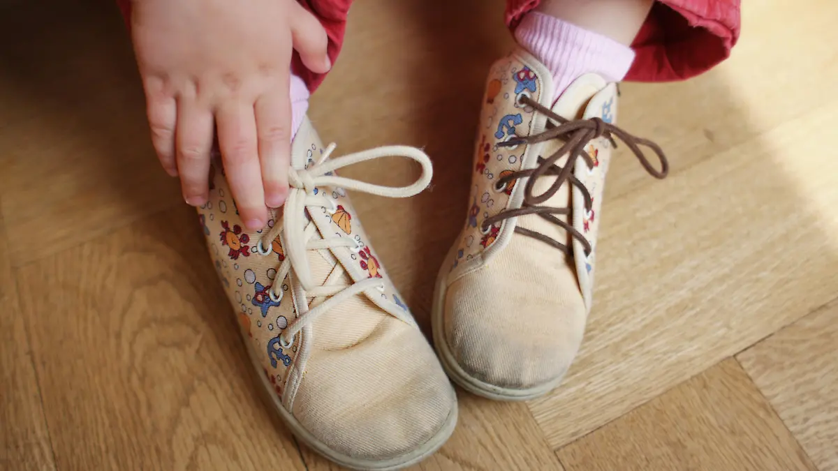 Symbolbild zum Thema Kinderarmut - Ein Kind (ein kleines Mädchen) trägt ein Paar stark abgetragene Schuhe aus Stoff mit verschiedenen Schnürsenkeln in Frankfurt am Main am 22.04.2009 (gestelltes Foto zur Illustration). Immer mehr Kinder in Deutschland leben in Armut und von Hartz 4 (Hartz IV). Ihre Eltern können oft selbst die einfachen Dinge des täglichen Bedarfs nicht mehr bezahlen. Foto: Wolfram Steinberg +++(c) dpa - Report+++
