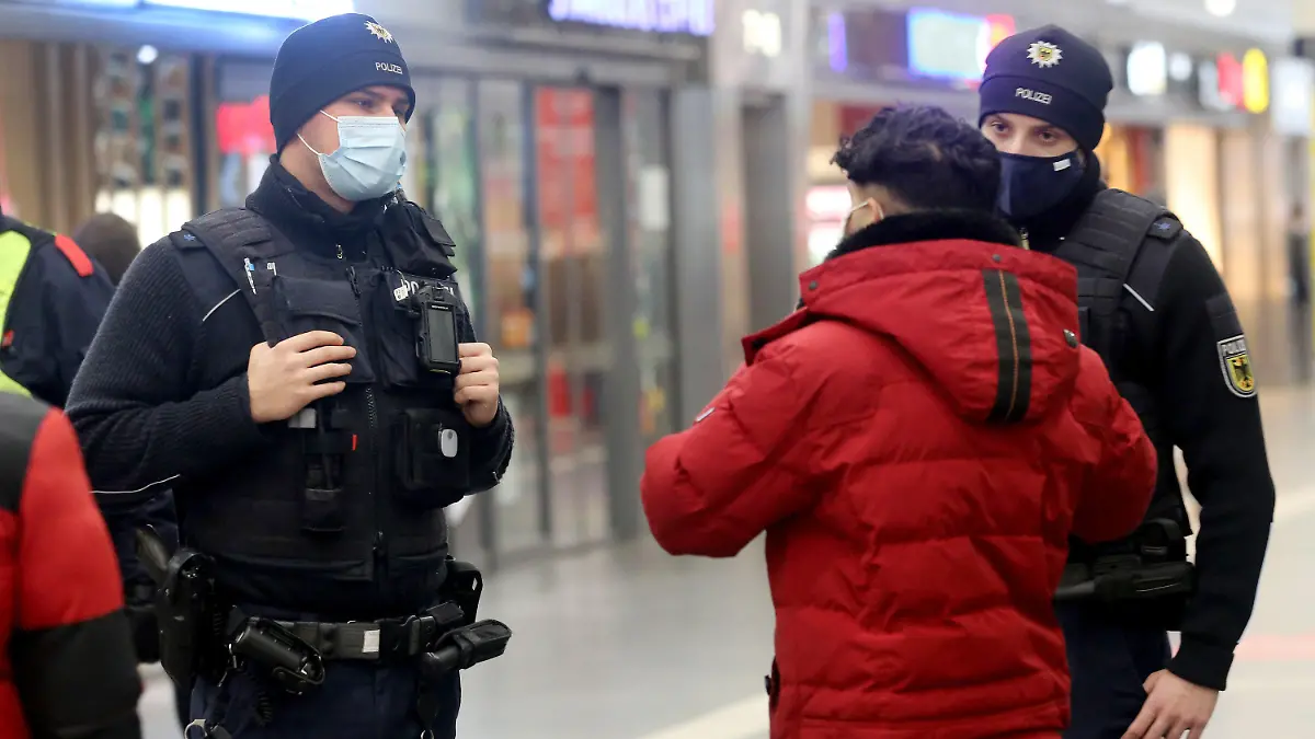 13.01.2021, Nordrhein-Westfalen, Essen: Zwei Bundespolizisten sprechen mit einer Bahnkund über das einwöchige Waffenverbot im Bahnhof. Ab sofort sei das Mitführen von Schuss-, Hieb- und Stichwaffen und Messern aller Art verboten. Foto: Roland Weihrauch/dpa +++ dpa-Bildfunk +++