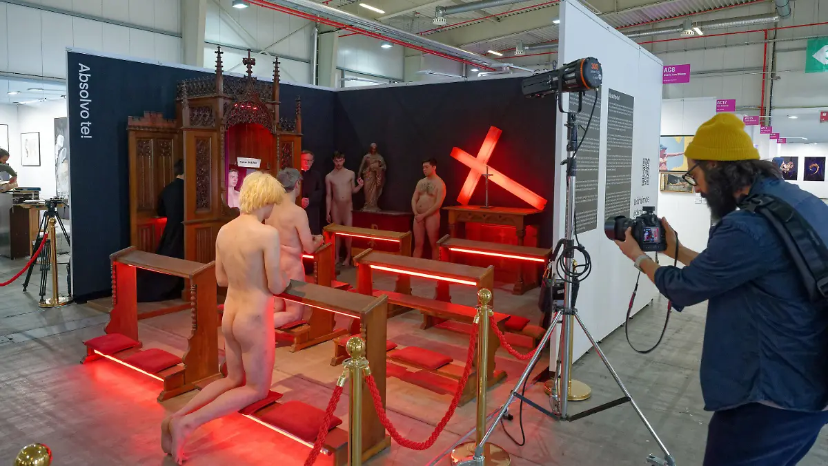 PRODUKTION - 20.04.2023, Nordrhein-Westfalen, Köln: Nackte Männer und zwei Männer in schwarzen Talaren agieren bei einer Kunstaktion. Bei der Inszenierung des Bonner Künstlers Dennis Josef Meseg auf der Discovery Art Fair Köln inszenieren sechs Aktmodelle «lebende Gemälde». Zur Kulisse gehört auch ein Beichtstuhl. Der Künstler will damit auf den Missbrauch in der katholischen Kirche und deren Umgang mit Tätern und Betroffenen aufmerksam machen. Foto: Henning Kaiser/dpa - ACHTUNG: Ein Teil des Bildes wurde aus rechtlichen Gründen gepixelt +++ dpa-Bildfunk +++