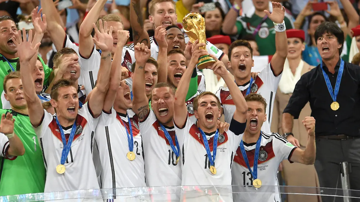 ARCHIV - Philipp Lahm (M) aus Germany hält am 13.07.2014 den WM-Pokal zwischen seinen Teamkollegen Torwart Manuel Neuer (vorne L-R), Miroslav Klose, Kevin Großkreutz, Lukas Podolski und Thomas Mueller; Bundestrainer Joachim Loew  (zweite Reihe R-L), Mesut Özil und Mario Götze nach dem gewonnen FIFA Finale der Fußball-Weltmeisterschaft 2014 zwischen Deutschland und Argentinien in Rio de Janeiro, Brasilien.   (RESTRICTIONS APPLY: Editorial Use Only, not used in association with any commercial entity - Images must not be used in any form of alert service or push service of any kind including via mobile alert services, downloads to mobile devices or MMS messaging - Images must appear as cstill images and must not emulate match action video footage - No alteration is made to, and no text or image is superimposed over, any published image which: (a) intentionally obscures or removes a sponsor identification image; or (b) adds or overlays the commercial identification of any third party which is not officially associated with the FIFA World Cup) EDITORIAL USE ONLY Foto: Andreas Gebert/dpa +++(c) dpa - Bildfunk+++