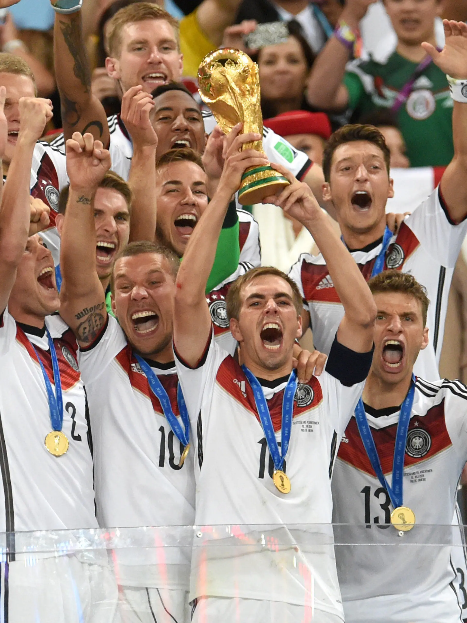 ARCHIV - Philipp Lahm (M) aus Germany hält am 13.07.2014 den WM-Pokal zwischen seinen Teamkollegen Torwart Manuel Neuer (vorne L-R), Miroslav Klose, Kevin Großkreutz, Lukas Podolski und Thomas Mueller; Bundestrainer Joachim Loew  (zweite Reihe R-L), Mesut Özil und Mario Götze nach dem gewonnen FIFA Finale der Fußball-Weltmeisterschaft 2014 zwischen Deutschland und Argentinien in Rio de Janeiro, Brasilien.   (RESTRICTIONS APPLY: Editorial Use Only, not used in association with any commercial entity - Images must not be used in any form of alert service or push service of any kind including via mobile alert services, downloads to mobile devices or MMS messaging - Images must appear as cstill images and must not emulate match action video footage - No alteration is made to, and no text or image is superimposed over, any published image which: (a) intentionally obscures or removes a sponsor identification image; or (b) adds or overlays the commercial identification of any third party which is not officially associated with the FIFA World Cup) EDITORIAL USE ONLY Foto: Andreas Gebert/dpa +++(c) dpa - Bildfunk+++