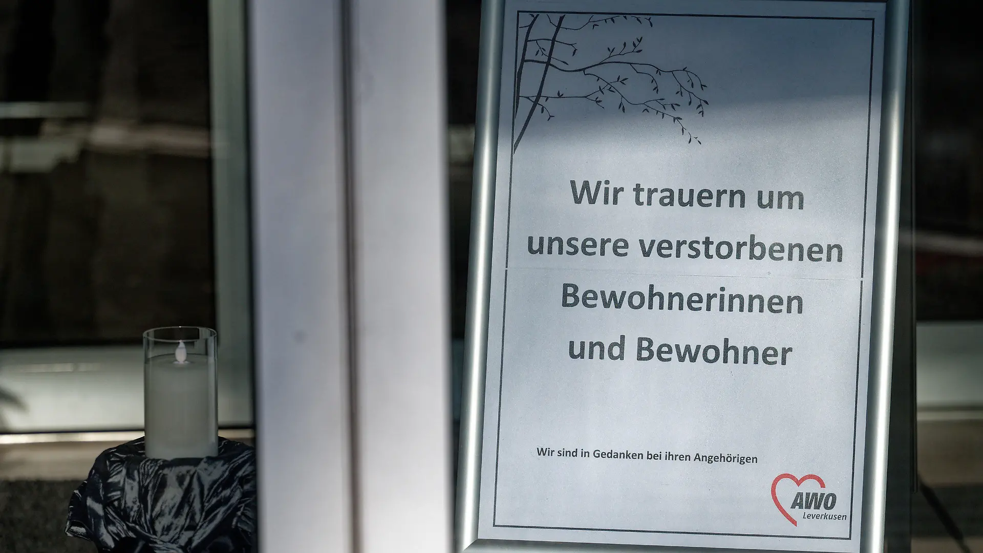 31.01.2021, Nordrhein-Westfalen, Leverkusen: Ein Schild mit der Aufschrift "Wir trauern um unsere verstorbenen Bewohner und Bewohnerinnen steht am Eingang des "AWO-Seniorenzentrum "Rheindorf" gGmbH". Nach einem Corona-Ausbruch in dem Seniorenzentrum sind dort 15 Bewohner gestorben. Insgesamt hätten sich 47 ältere Menschen und 25 Mitarbeiter angesteckt, sagte eine Sprecherin der Stadt Leverkusen am Sonntag. In dem Seniorenheim sei die als besonders ansteckend geltende Mutation B 1.1.7 des Erregers Sars-CoV-2 nachgewiesen worden. Foto: Henning Kaiser/dpa +++ dpa-Bildfunk +++