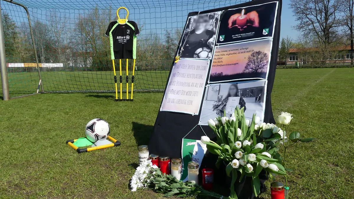 21.04.2023, Klötze: Auf dem Sportplatz von Klötze stehen Kerzen, Blumen und ein Aufsteller zum Gedenken an eine 19-Jährige, die jetzt tot aufgefunden wurde. Ein 42-Jähriger wurde wegen des dringenden Tatverdachts des Totschlags festgenommen. Foto: --/dpa +++ dpa-Bildfunk +++