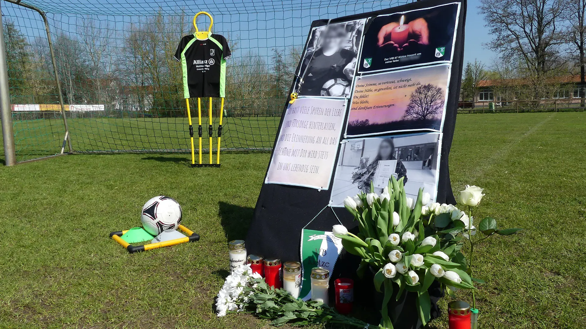 21.04.2023, Klötze: Auf dem Sportplatz von Klötze stehen Kerzen, Blumen und ein Aufsteller zum Gedenken an eine 19-Jährige, die jetzt tot aufgefunden wurde. Ein 42-Jähriger wurde wegen des dringenden Tatverdachts des Totschlags festgenommen. Foto: --/dpa +++ dpa-Bildfunk +++