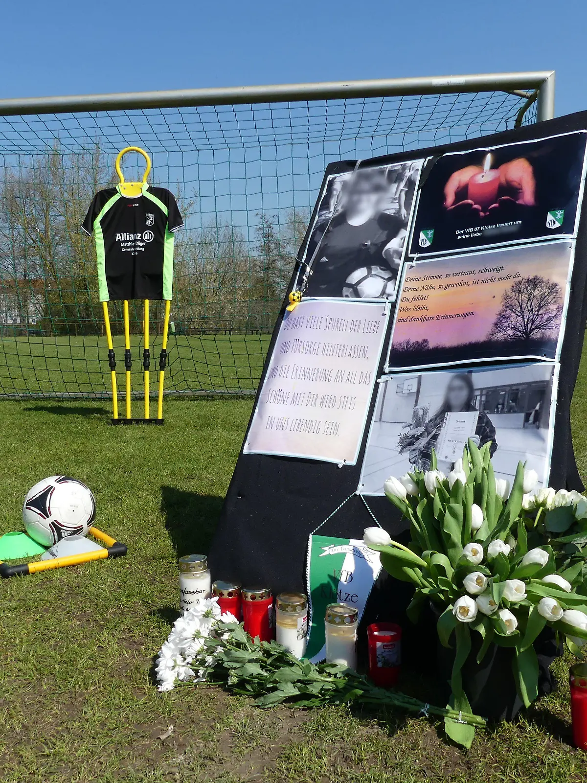 21.04.2023, Klötze: Auf dem Sportplatz von Klötze stehen Kerzen, Blumen und ein Aufsteller zum Gedenken an eine 19-Jährige, die jetzt tot aufgefunden wurde. Ein 42-Jähriger wurde wegen des dringenden Tatverdachts des Totschlags festgenommen. Foto: --/dpa +++ dpa-Bildfunk +++