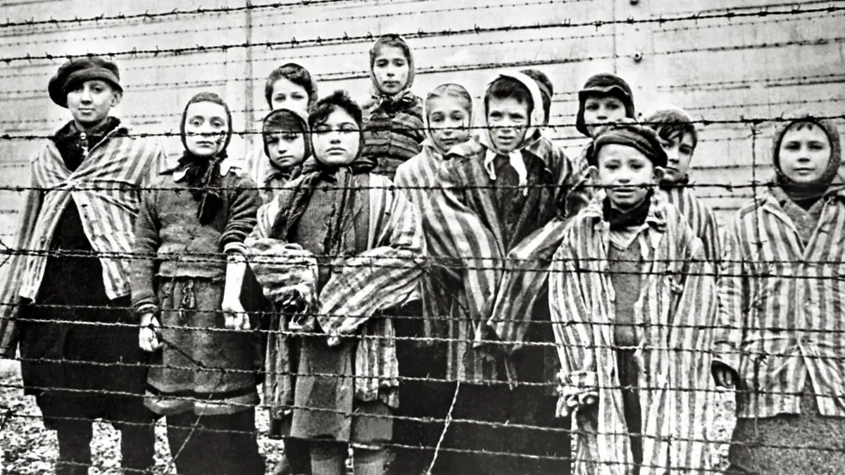  Überlebende jüdische Kinder in Auschwitz Mit Krankenschwester hinter Stacheldrahtzaun. Das Foto wurde von einem sowjetischen Fotografen während der Herstellung eines Films über Befreiung des Lagers gemacht. Die Kinder wurden von den Russen mit Kleidung von erwachsenen Gefangenen verkleidet. Auschwitz, Polen. Datum: Februar 1945 *** Surviving Jewish children in Auschwitz with nurse behind barbed wire fence. The photo was taken by a soviet photographer while making a film about liberation of the camp. The children were disguised by the Russians with clothes of adult prisoners. Auschwitz Poland. Date of February, 1945