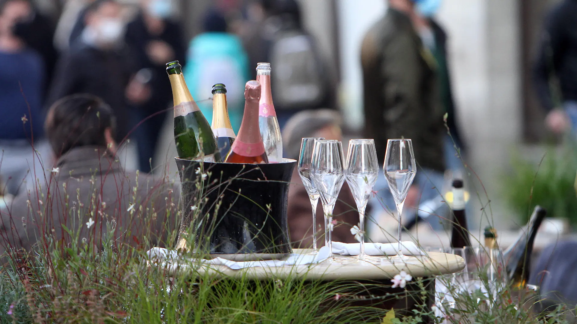 Champagner und Weinflaschen stehen mit Gläsern im gut besuchten Außenbereich des Restaurants Dallmayr in der Altstadt von München, Bayern, Deutschland *** Champagne and wine bottles are standing with glasses in the well-attended outdoor area of Restaurant Dallmayr in the old town of Munich, Bavaria, Germany