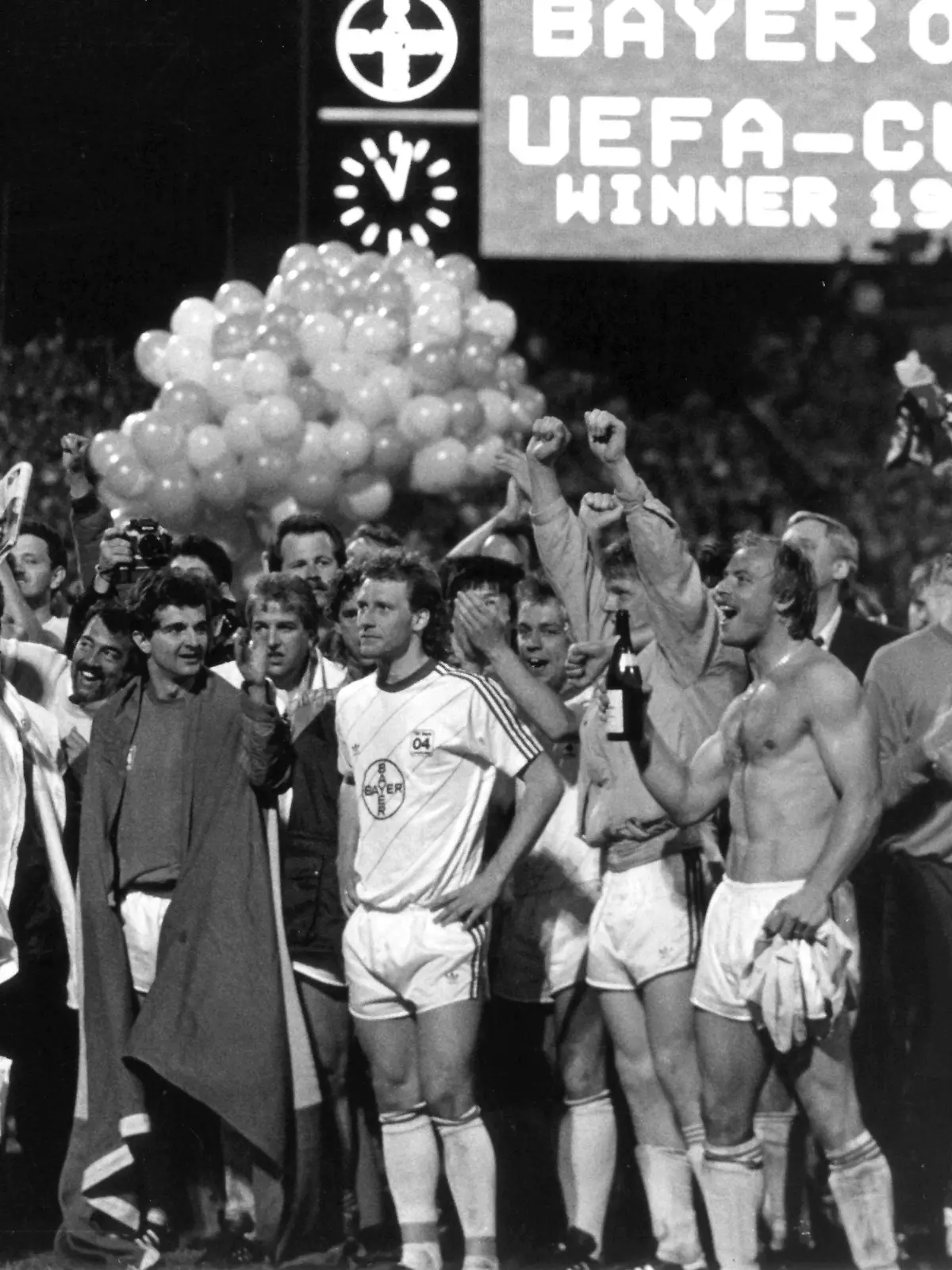 Die Spieler von Bayer Leverkusen mit Torhüter Rüdiger Vollborn (r) und Abwehrakteur Wolfgang Rolff (M, mit Trikot) feiern am 18.5.1988 im heimischen Stadion mit ihren Fans den Gewinn des UEFA-Cups. In einer furiosen Aufholjagd macht Leverkusen im Finalrückspiel gegen Espanol Barcelona ein 0:3 aus dem Hinspiel wett. Am Ende der regulären Spielzeit und der Verlängerung steht es 3:0, und dann gewinnt Bayer Leverkusen das fällig Elfmeterschießen mit 3:2 - der größte Erfolg in der 84jährigen Vereinsgeschichte ist perfekt.