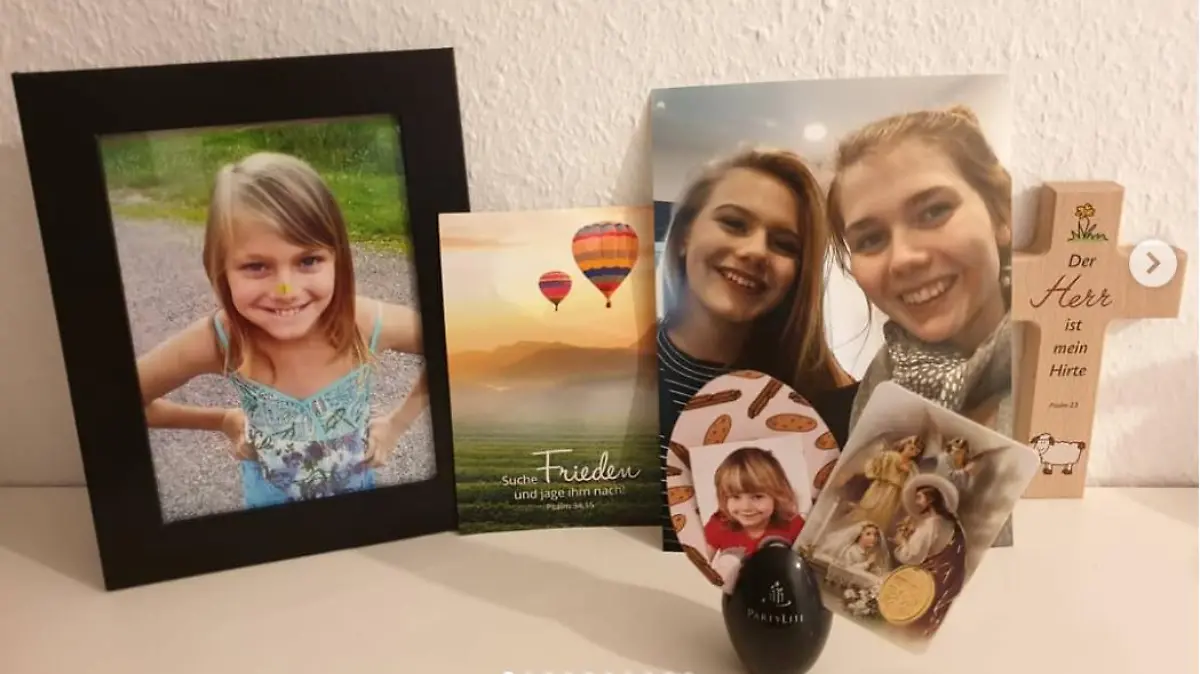 Ein Kreuz und ein schwarz eingerahmtes Bild von Rebecca Reusch.