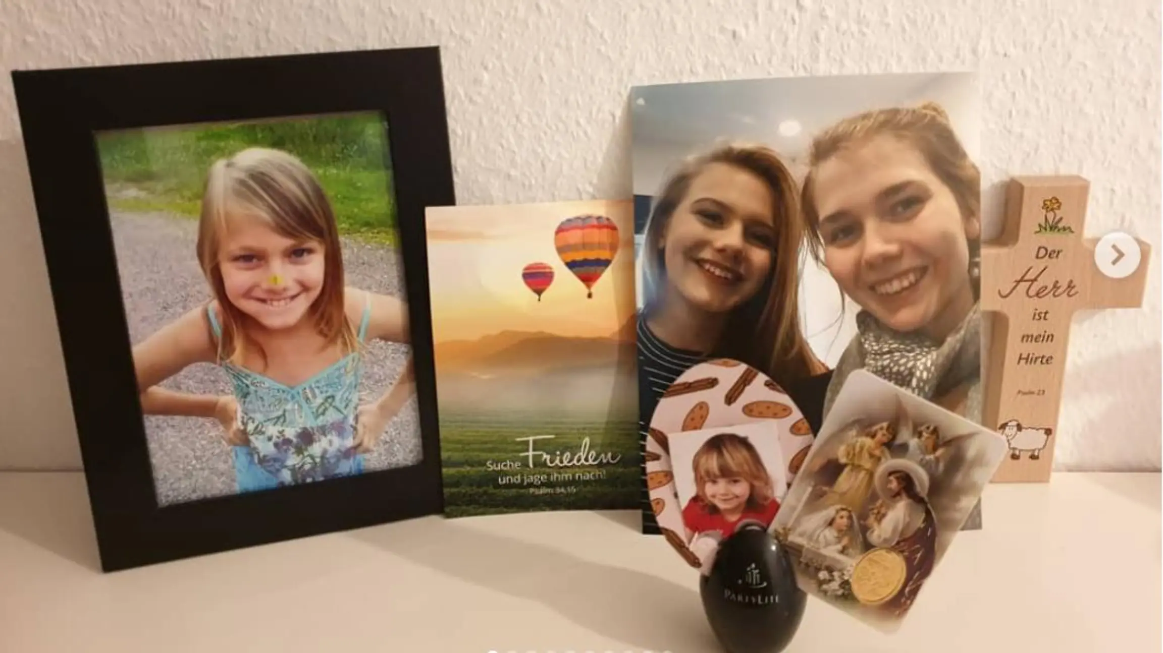 Ein Kreuz und ein schwarz eingerahmtes Bild von Rebecca Reusch.