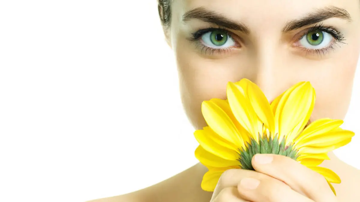 closeup of a pretty young woman smelling a yellow flower