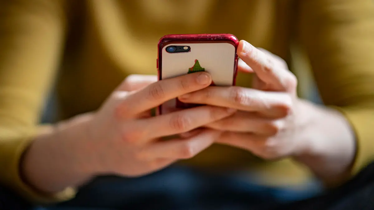 ARCHIV - 24.04.2021, Berlin: Eine junge Frau hält ein Smartphone in der Hand. (zu dpa «Studie der Uni Bochum: Weniger Smartphone, mehr Wohlbefinden») Foto: Fabian Sommer/dpa +++ dpa-Bildfunk +++