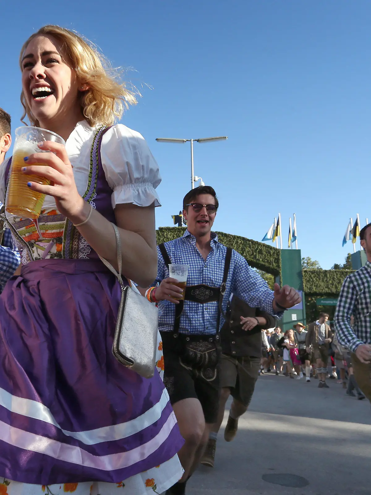 21.09.2019, Bayern, München: Auftakt zum Oktoberfest. Oktoberfestbesucher stürmen nach der Eröffnung mit Bier in der Hand lachend auf die Wiesn. Das größte Volksfest der Welt dauert bis zum 6. Oktober. Foto: Karl-Josef Hildenbrand/dpa +++ dpa-Bildfunk +++