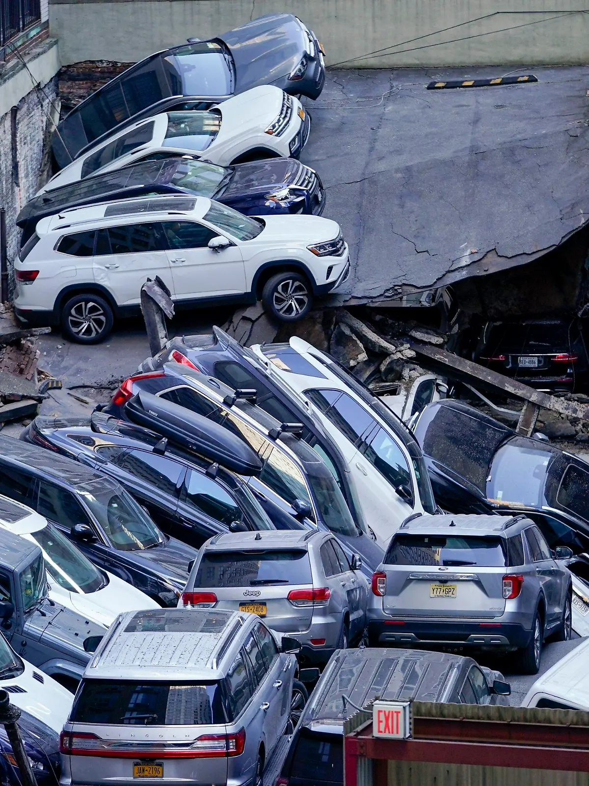dpatopbilder - 18.04.2023, USA, New York: An der Stelle, an der ein Parkhaus im Financial District von New York teilweise eingestürzt ist, stapeln sich Autos übereinander. Zahlreiche Autos wurden zusammengedrückt. Die Rettungsarbeiten mussten zeitweise unterbrochen werden, weil das größtenteils in sich zusammengesackte Parkhaus an der Südspitze Manhattans noch weiter einzustürzen drohte. Foto: Mary Altaffer/AP/dpa +++ dpa-Bildfunk +++
