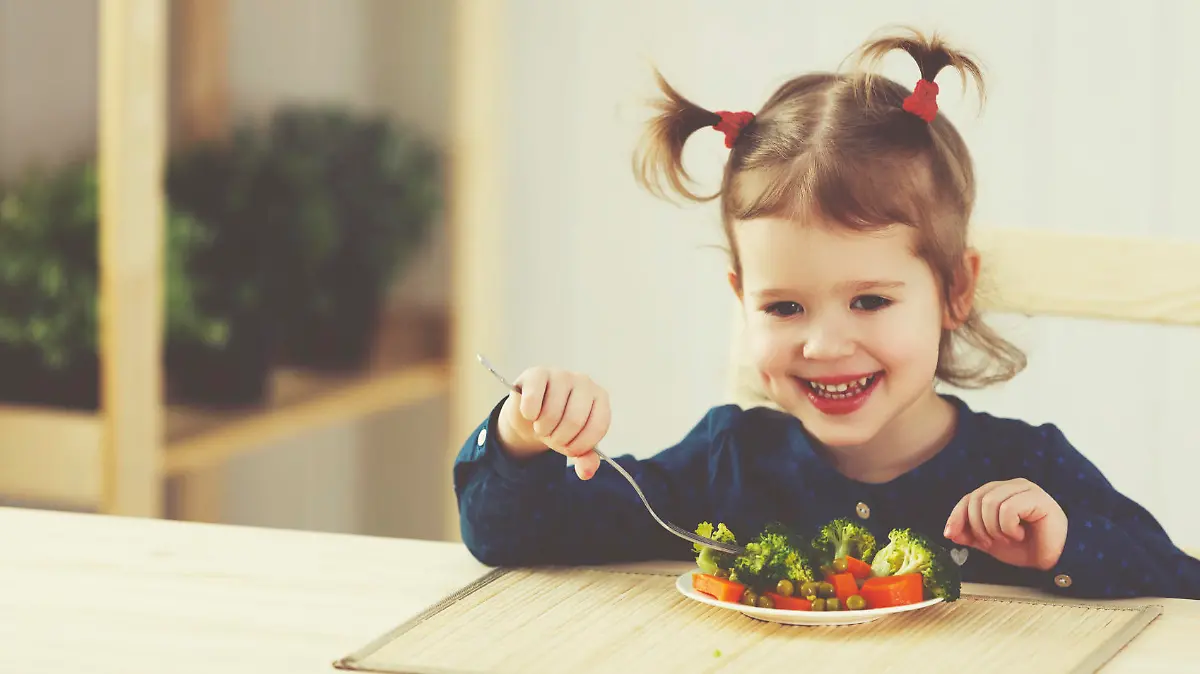 the happy child girl eating vegetables and laughs