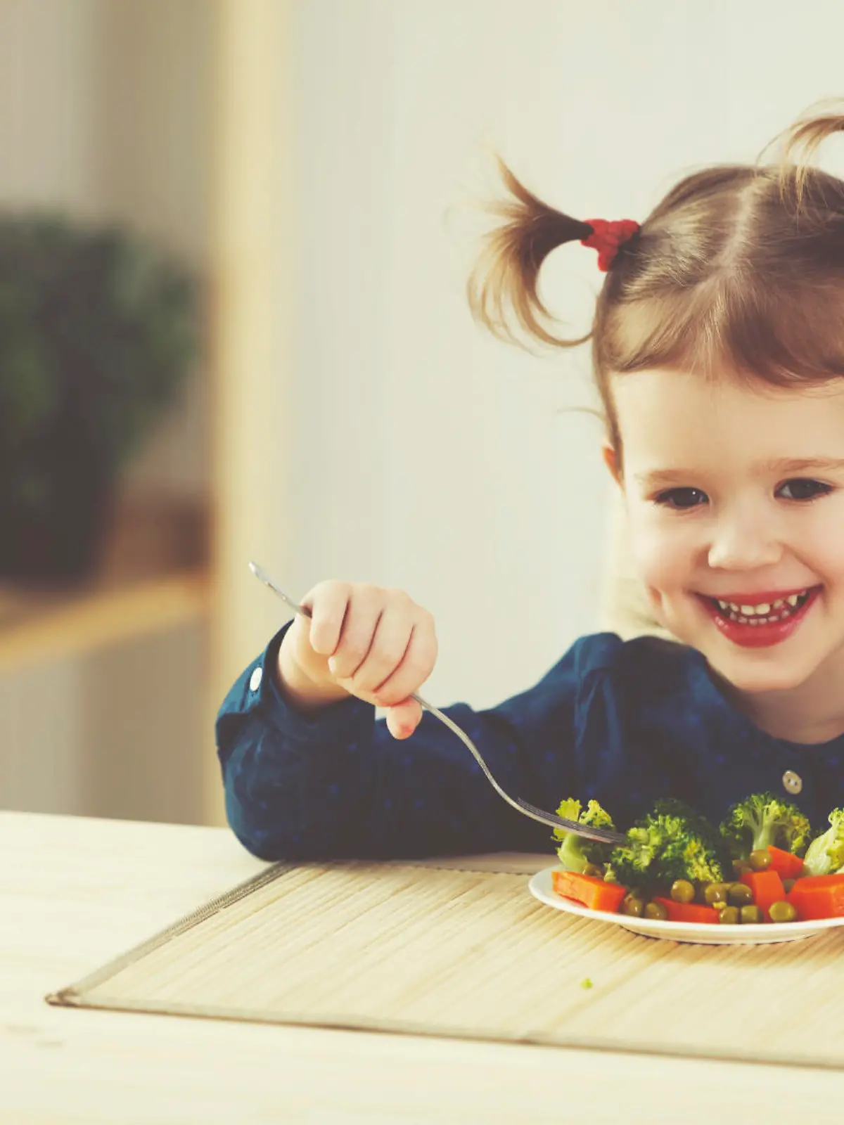 the happy child girl  eating vegetables and laughs