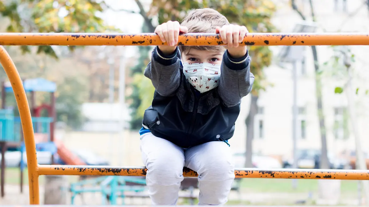 Kind mit Maske auf Spielplatz