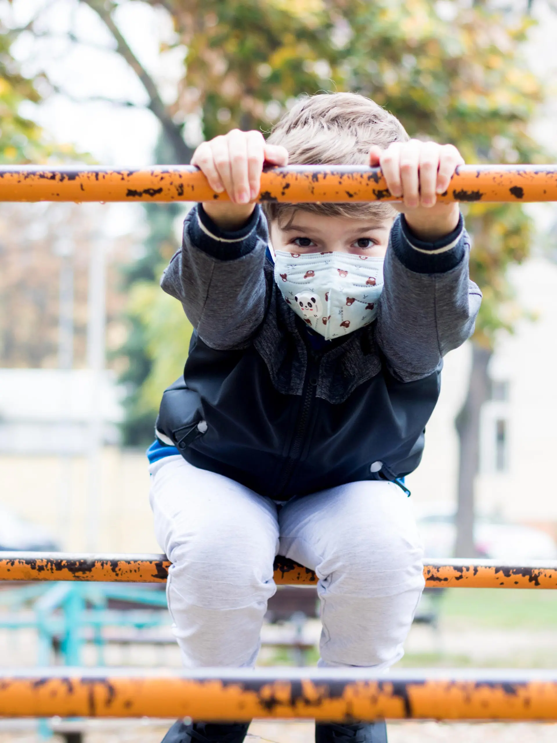 Kind mit Maske auf Spielplatz
