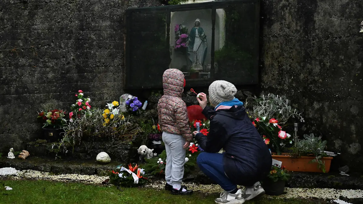 Denise Gormley and her daughter Rosa, 7, pay their respects and blow bubbles at the Tuam graveyard, where the bodies of 796 babies were uncovered at the site of a former Catholic home for unmarried mothers and their children, on the day a government-ordered inquiry into former Church-run homes for unmarried mothers is formally published, in Tuam, Ireland, January 12, 2021. REUTERS/Clodagh Kilcoyne