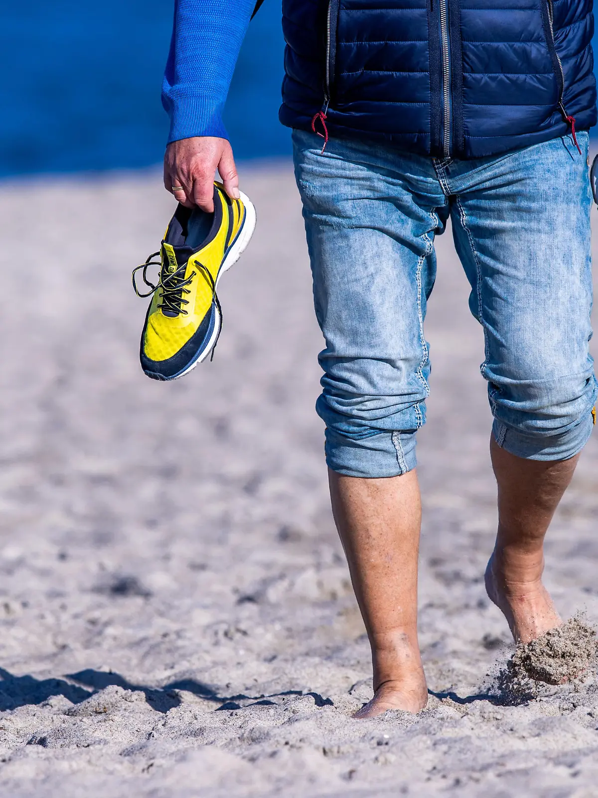 Ein Urlauber geht bei Sonnenschein barfuß am Strand auf der Ostseeinsel Poel spazieren. Sonnig und mit Temperaturen um die 15 Grad zeigt sich das Herbstwetter in Norddeutschland von seiner freundlichen Seite.