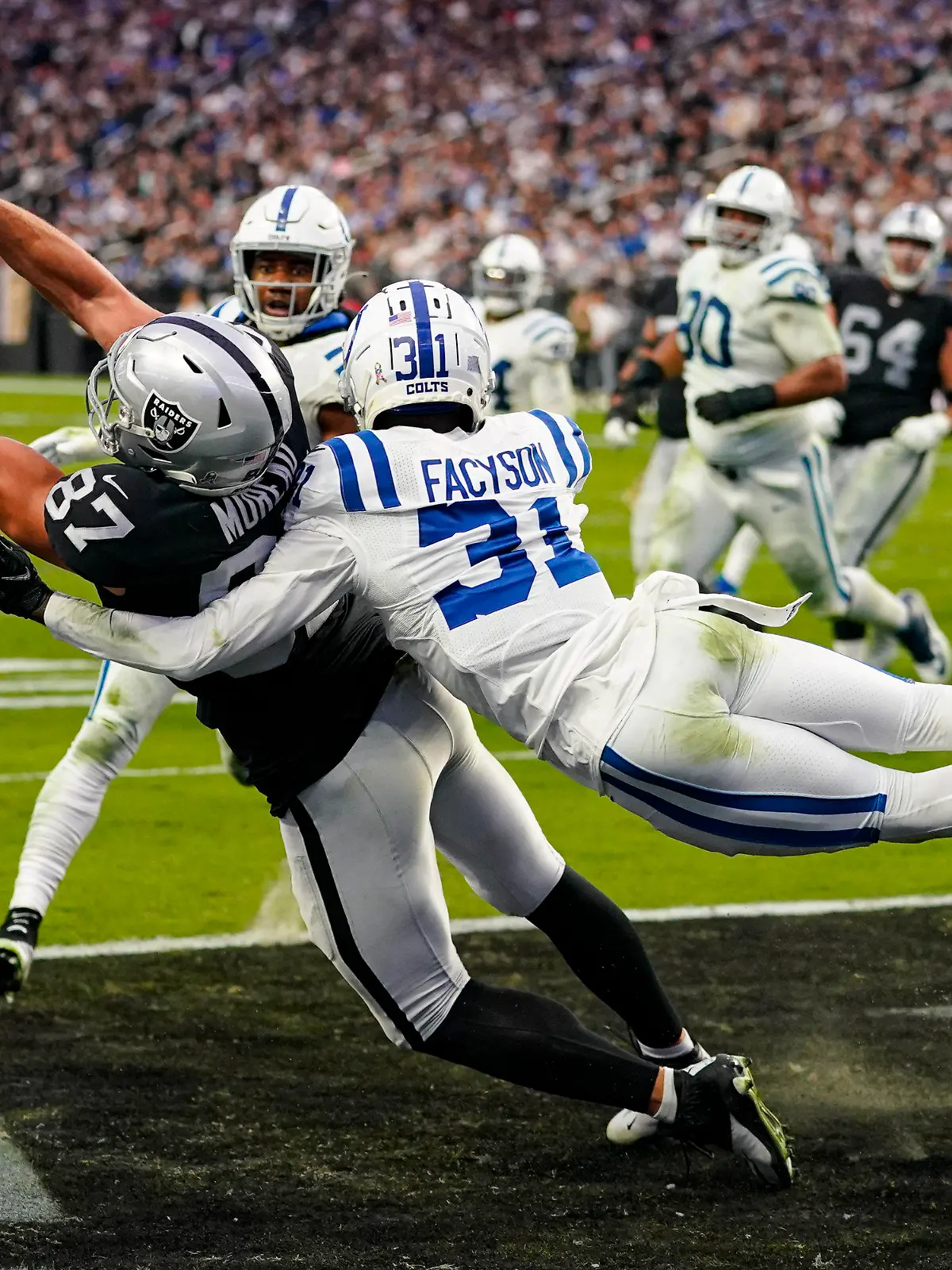 ARCHIV - 13.11.2022, USA, Las Vegas: Foster Moreau (87) von Las Vegas Raiders fängt einen Touchdown, während er von Indianapolis Colts Cornerback Brandon Facyson (31) angegriffen wird. (Archiv). Moreau hat nun eine Krebserkrankung öffentlich gemacht (zu dpa: «Bei Routinekontrolle festgestellt: NFL-Profi an Krebs erkrankt») Foto: Matt York/AP/dpa +++ dpa-Bildfunk +++