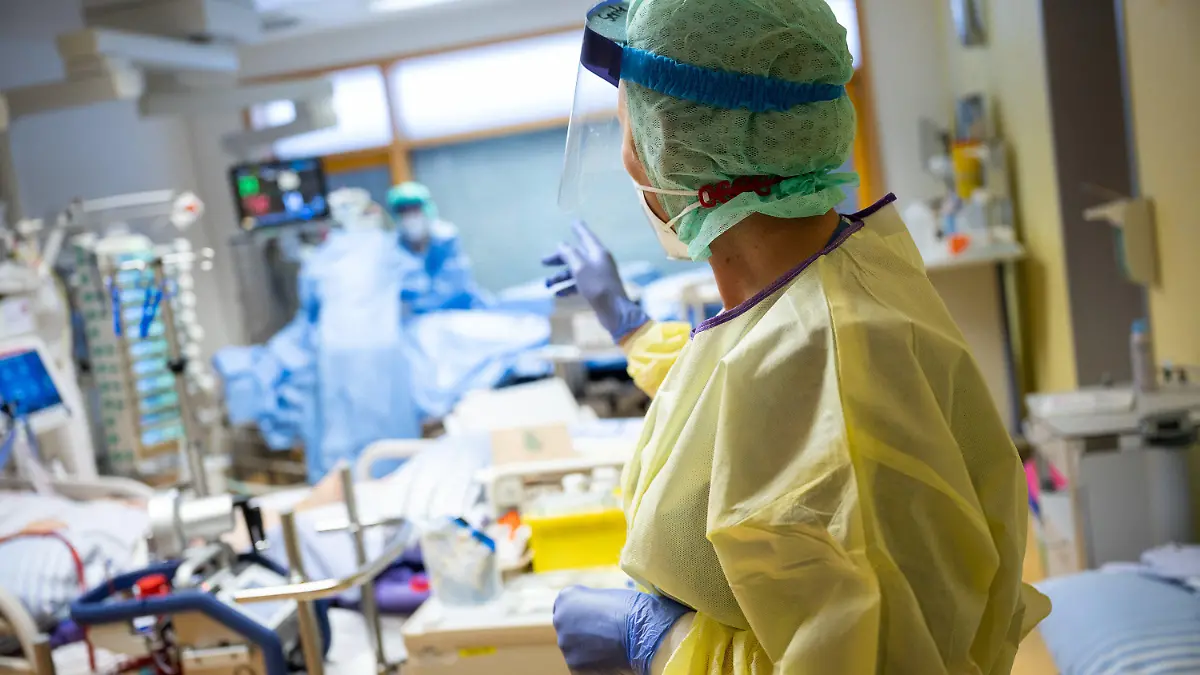 08.01.2021, Baden-Württemberg, Ludwigsburg: Eine Intensivkrankenschwester steht auf einer Intensivstation des RKH Klinikum Ludwigsburg im Zimmer eines Covid-19-Patienten. In Baden-Württemberg wird die Belegung der Intensivstationen mit einem Clusterkonzept gesteuert. Zwischen den Kliniken der sechs Versorgungsgebiete können Intensivpatienten verlegt werden, um eine bessere Verteilung zwischen den Krankenhäusern zu erreichen. Foto: Sebastian Gollnow/dpa +++ dpa-Bildfunk +++