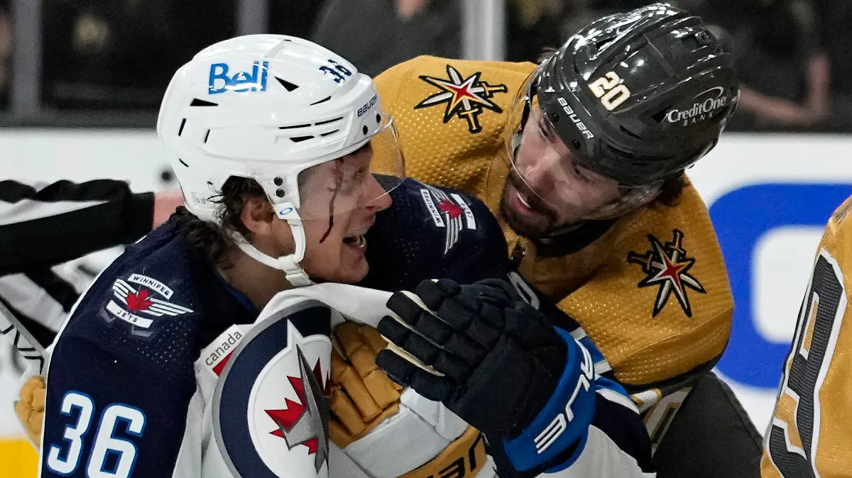 Vegas Golden Knights center Chandler Stephenson (20) helps Winnipeg Jets center Morgan Barron (36) after Barron cut his face on a skate during the first period of Game 1 of an NHL hockey Stanley Cup first-round playoff series Tuesday, April 18, 2023, in Las Vegas. (AP Photo/John Locher)