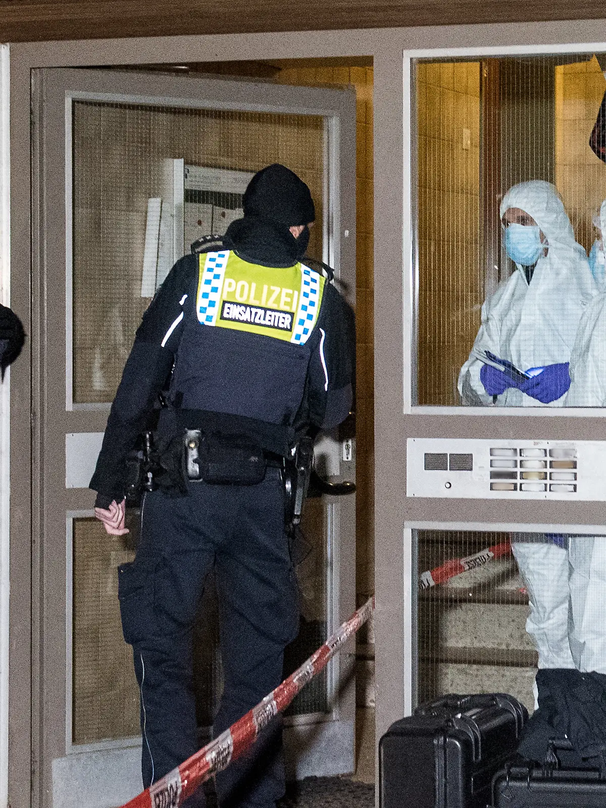 10.01.2021, Hamburg: Polizisten und Mitarbeiter der Spurensicherung stehen im Stadtteil Neuallermöhe im Eingang eines Mehrfamilienhauses. Bei einer Gewalttat ist am Sonntag in dem Haus eine Frau getötet worden. Foto: Daniel Bockwoldt/dpa +++ dpa-Bildfunk +++