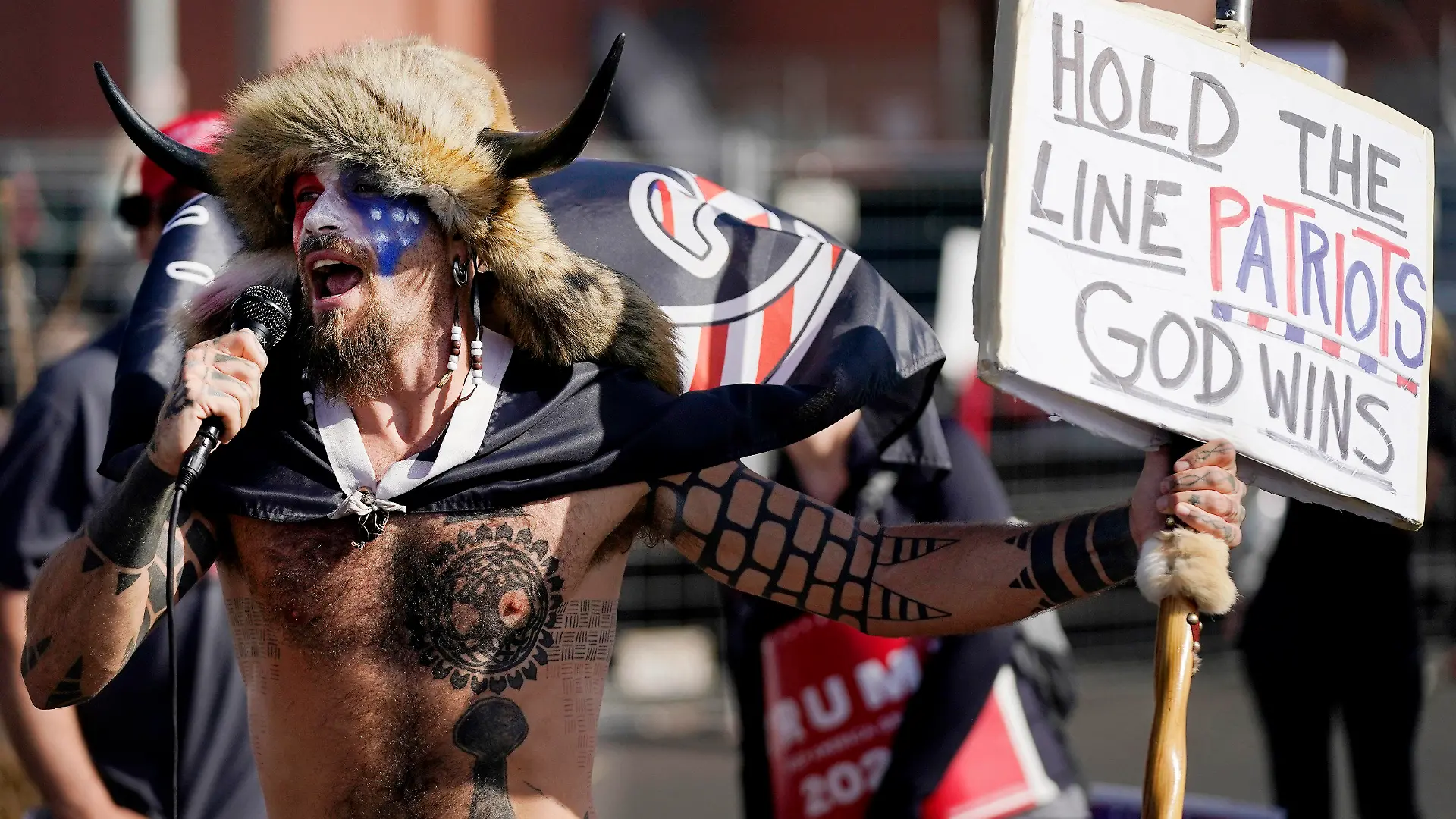 Jake Angeli, a supporter of President Donald Trump, speaks at a rally outside the Maricopa County Recorder's Office Saturday, Nov. 7, 2020, in Phoenix. Democrat Joe Biden defeated President Donald Trump to become the 46th president of the United States on Saturday, positioning himself to lead a nation gripped by the historic pandemic and a confluence of economic and social turmoil. (AP Photo/Ross D. Franklin)