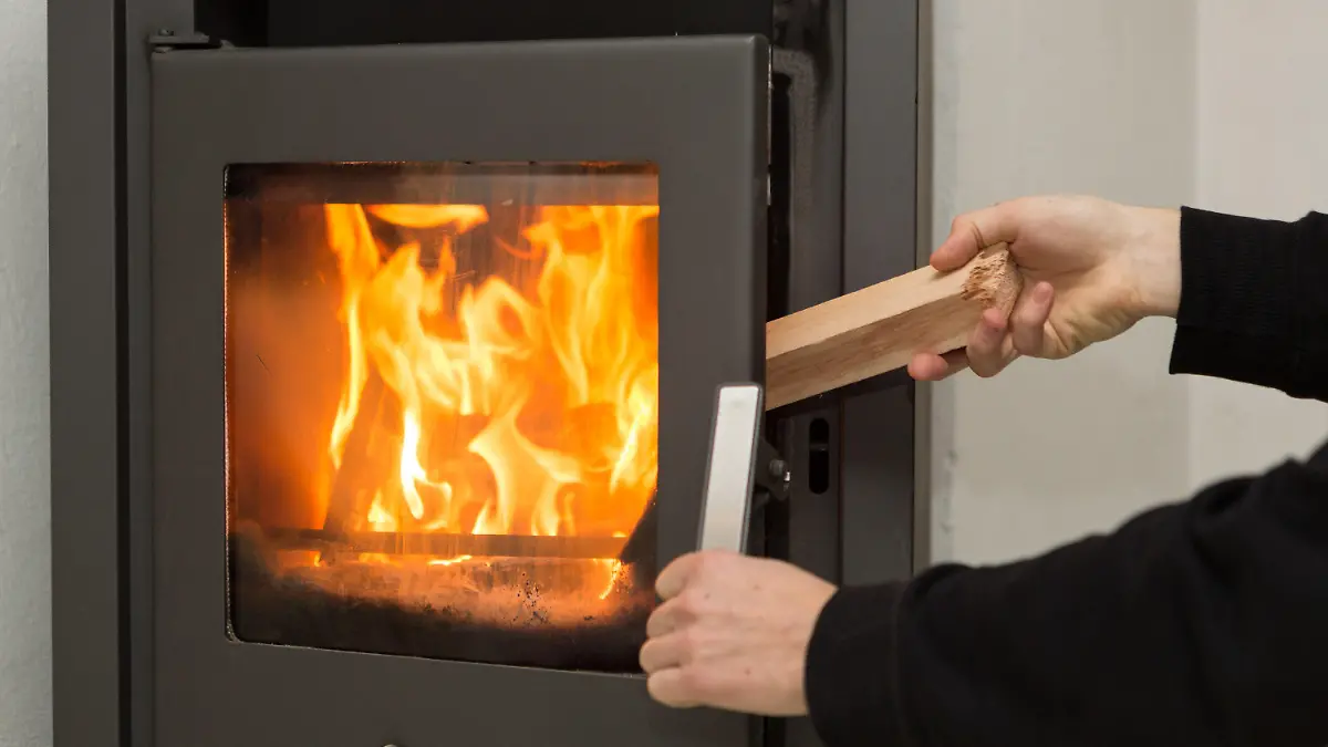 ARCHIV - 02.01.2017, Baden-Württemberg, Rottweil: Ein Mann legt in seiner Wohnung ein Stück Holz in einen Kaminofen, in dem ein Feuer brennt. Die Feinstaubimmissionen im Land bewegen sich nach Angaben der Landesanstalt für Umwelt Baden-Württemberg (LUBW) seit Weihnachten weiter auf einem niedrigen Niveau - auch dank des zu großen Teilen milden und wechselhaften Winters. (zu dpa: «Kaum dicke Luft im Südwesten - Wie schädlich sind Holzöfen?») Foto: Silas Stein/dpa +++ dpa-Bildfunk +++