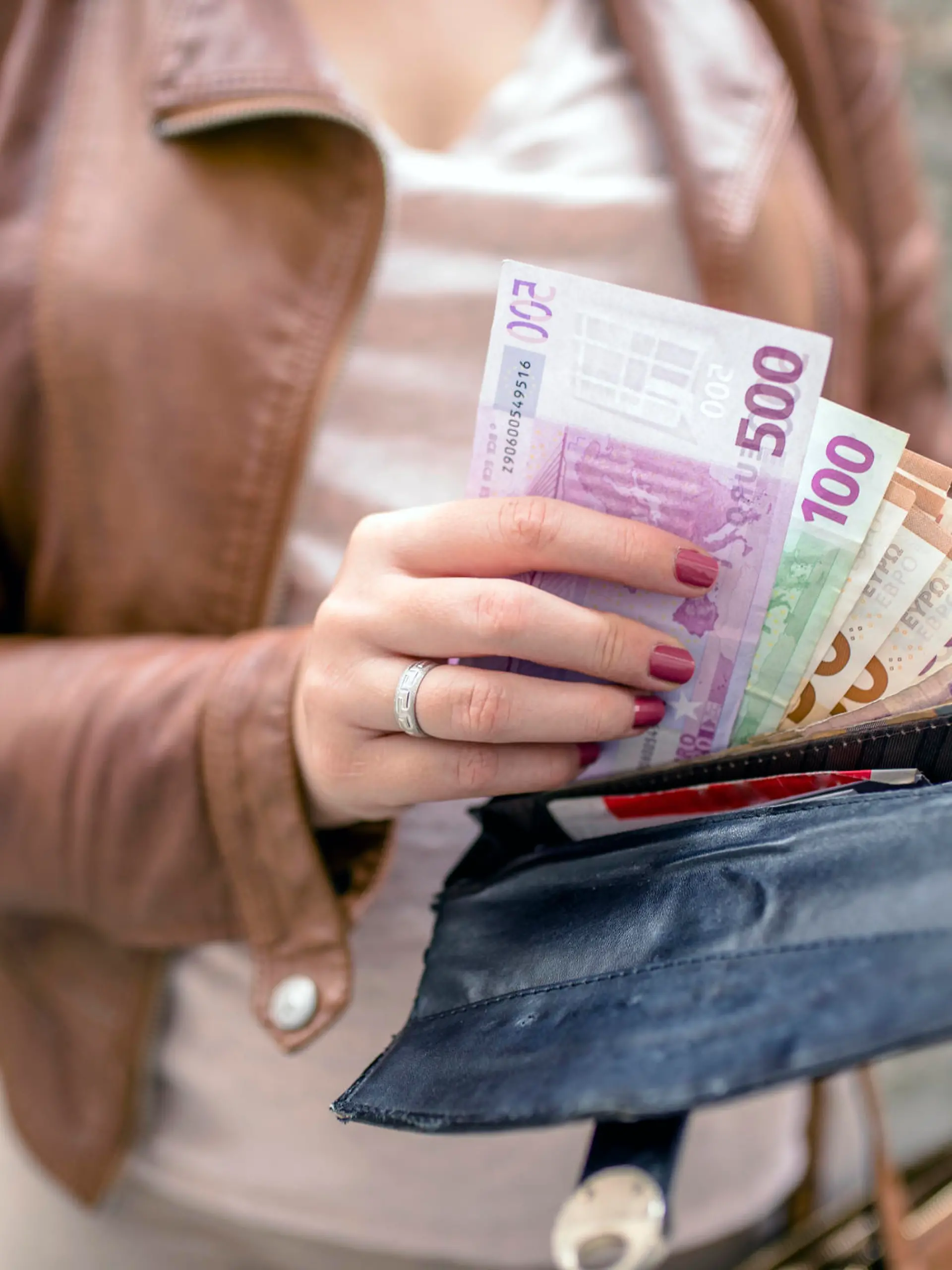 Frau steckt Geld ins Portemonnaie