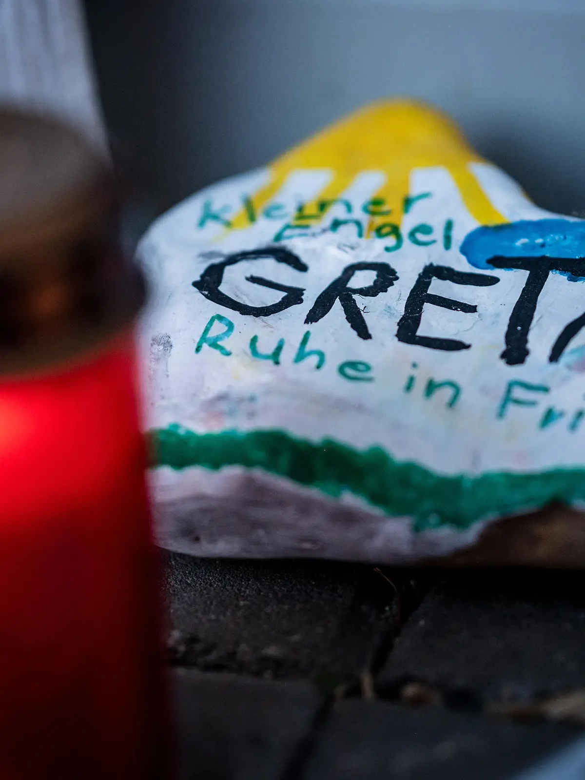 Bemalte Steine und Kerzen liegen vor dem Eingang einer Kindertagesstätte.