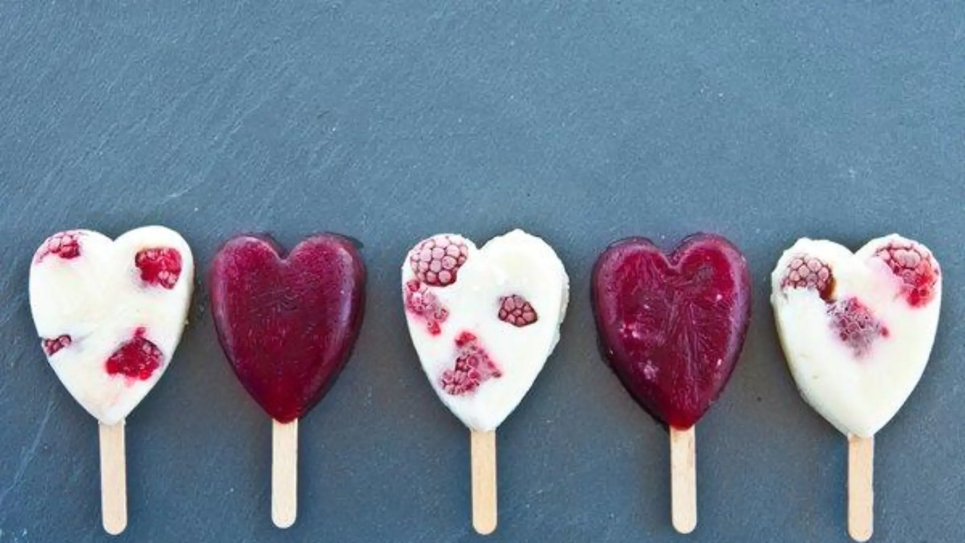 Eis am Stiel in Herzform mit frischen Himbeeren