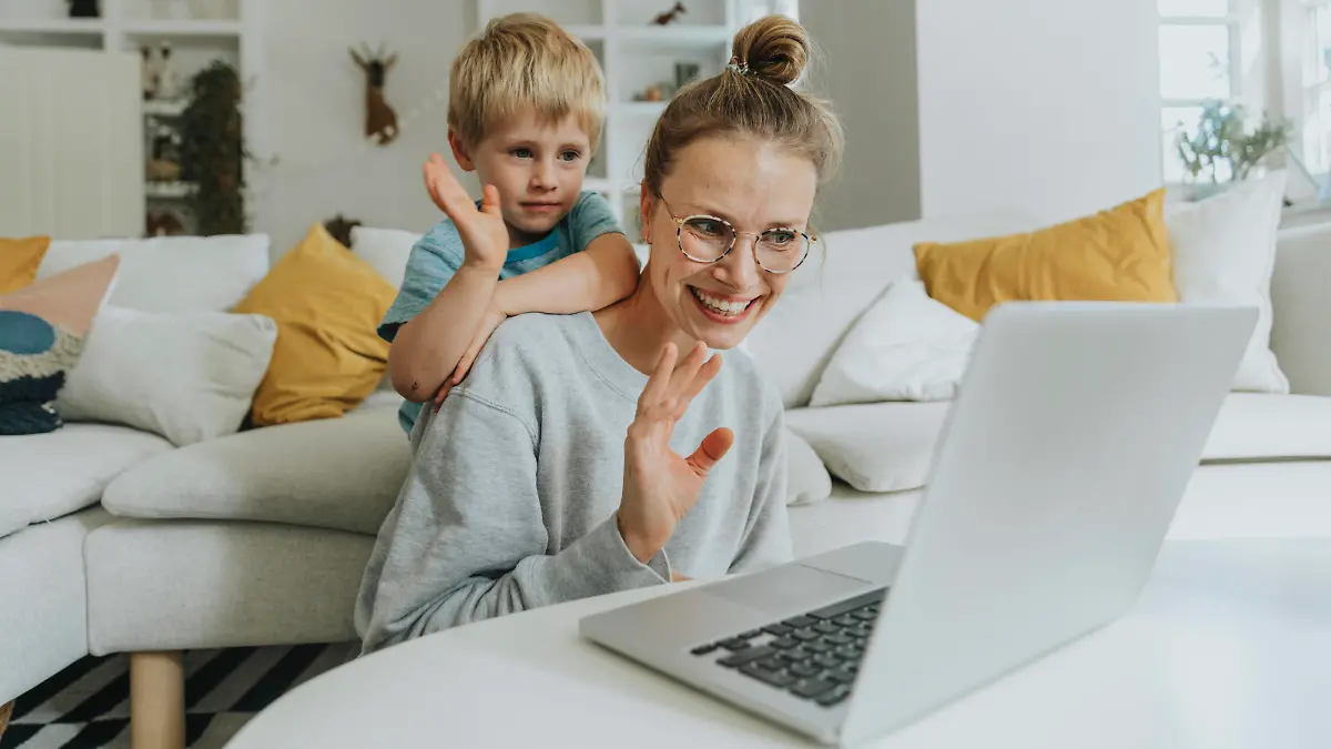  Mother and son waving hand to video call on laptop while sitting at home model released Symbolfoto property released MFF06215