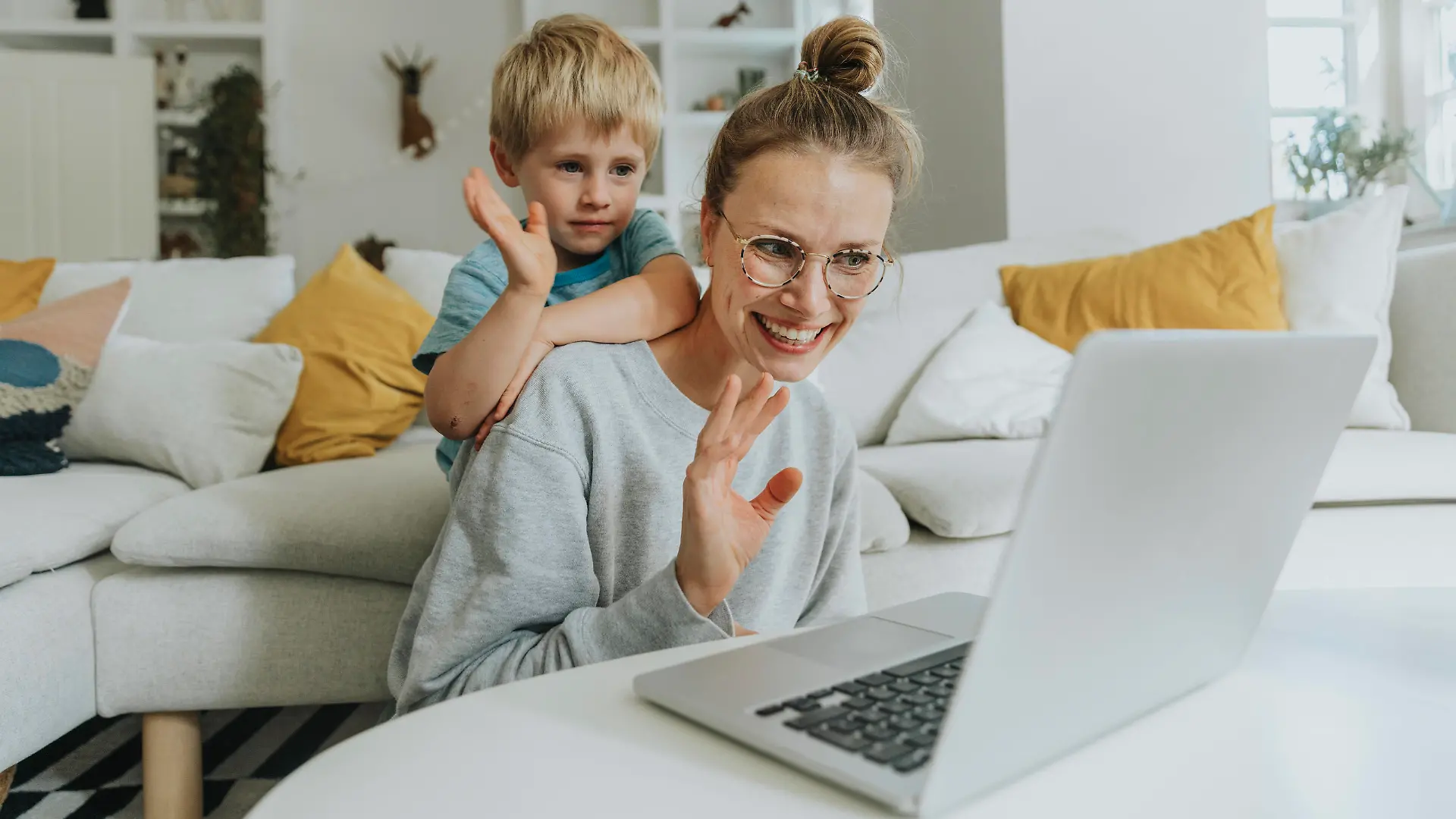 Mother and son waving hand to video call on laptop while sitting at home model released Symbolfoto property released MFF06215