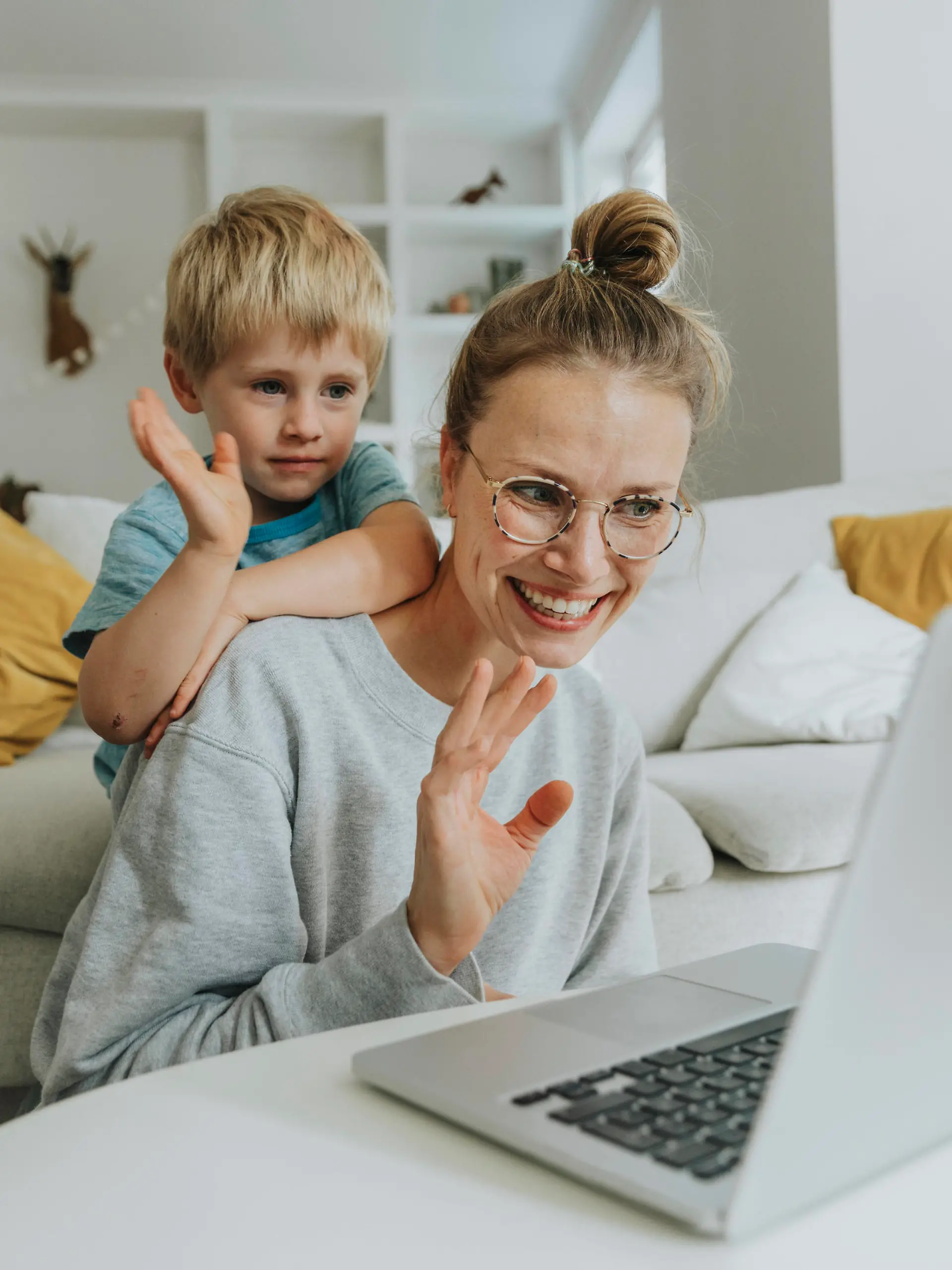  Mother and son waving hand to video call on laptop while sitting at home model released Symbolfoto property released MFF06215