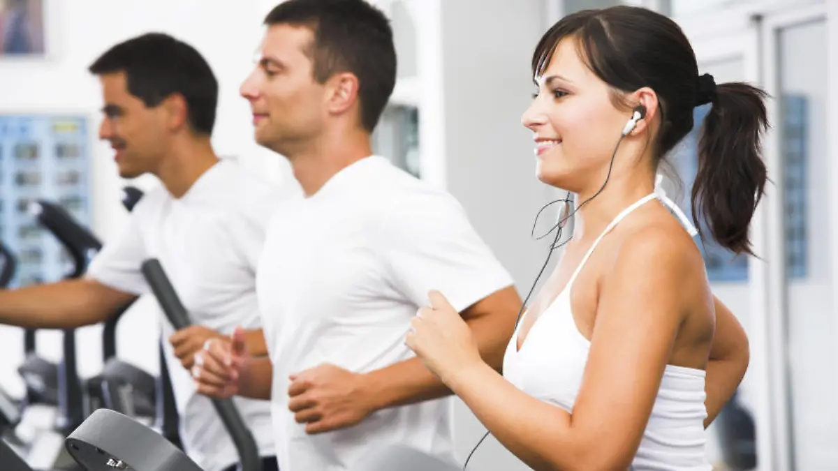Young adults using running machine at the fitness club
