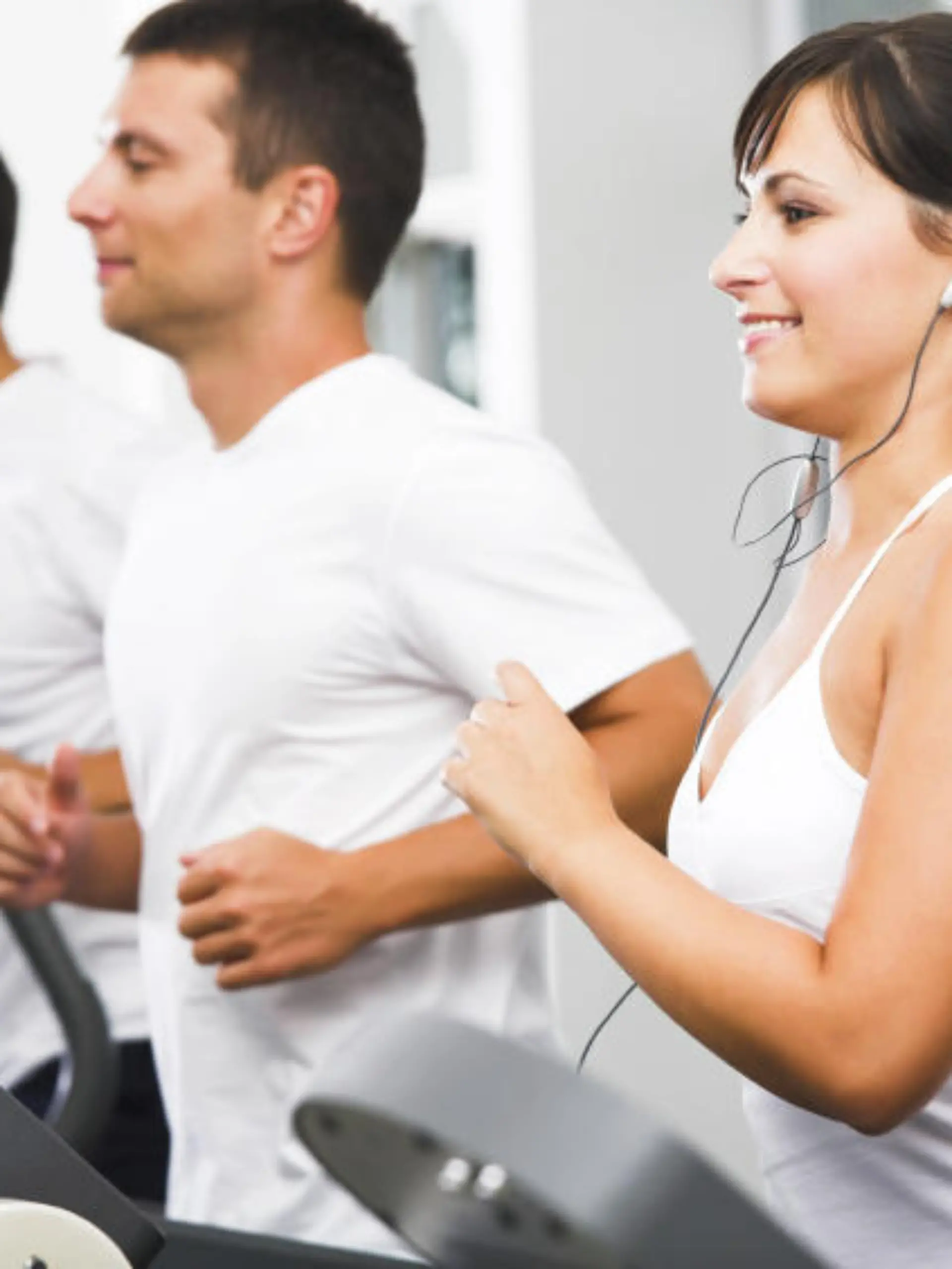 Young adults using running machine at the fitness club