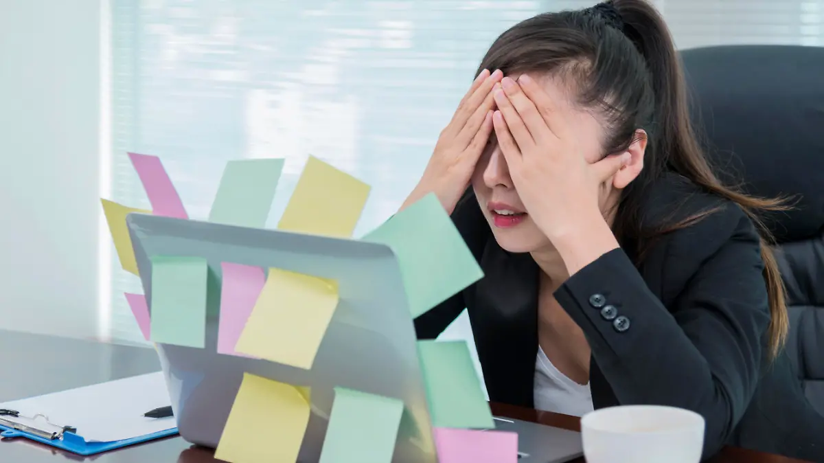 Businesswoman sleeping in office, with many adhesive notes on laptop.
