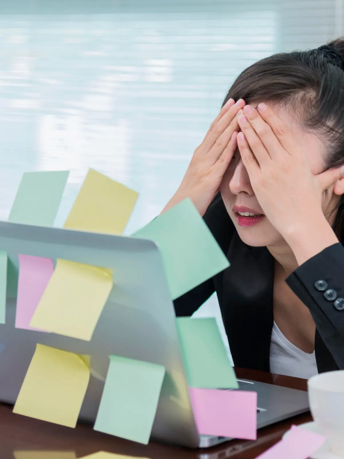 Businesswoman sleeping in office, with many adhesive notes on laptop.