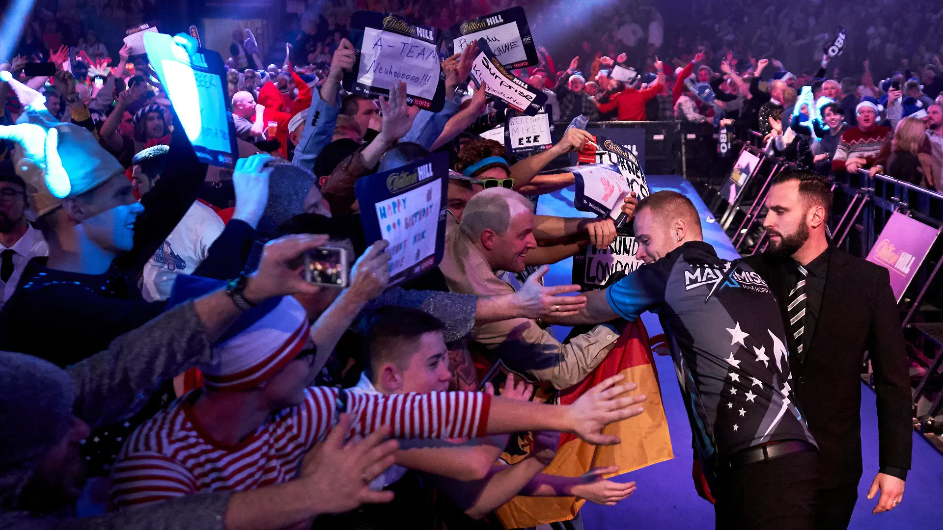 ARCHIV - 20.12.2019, Großbritannien, London: Darts: WM, Alexandra Palace, Hopp (Deutschland) - van de Pas (Niederlande): Max Hopp kommt zu seinem Spiel gegen van de Pas und begrüßt die Fans. Verkleidet kommen, besoffen gehen - unter diesem Motto steht für viele Fans ein Besuch bei der Darts-WM. (zu dpa: «Für 22 Pfund Richtung Rausch: Darts als Festival ohne jede Grenze»). Foto: John Walton/PA Wire/dpa +++ dpa-Bildfunk +++