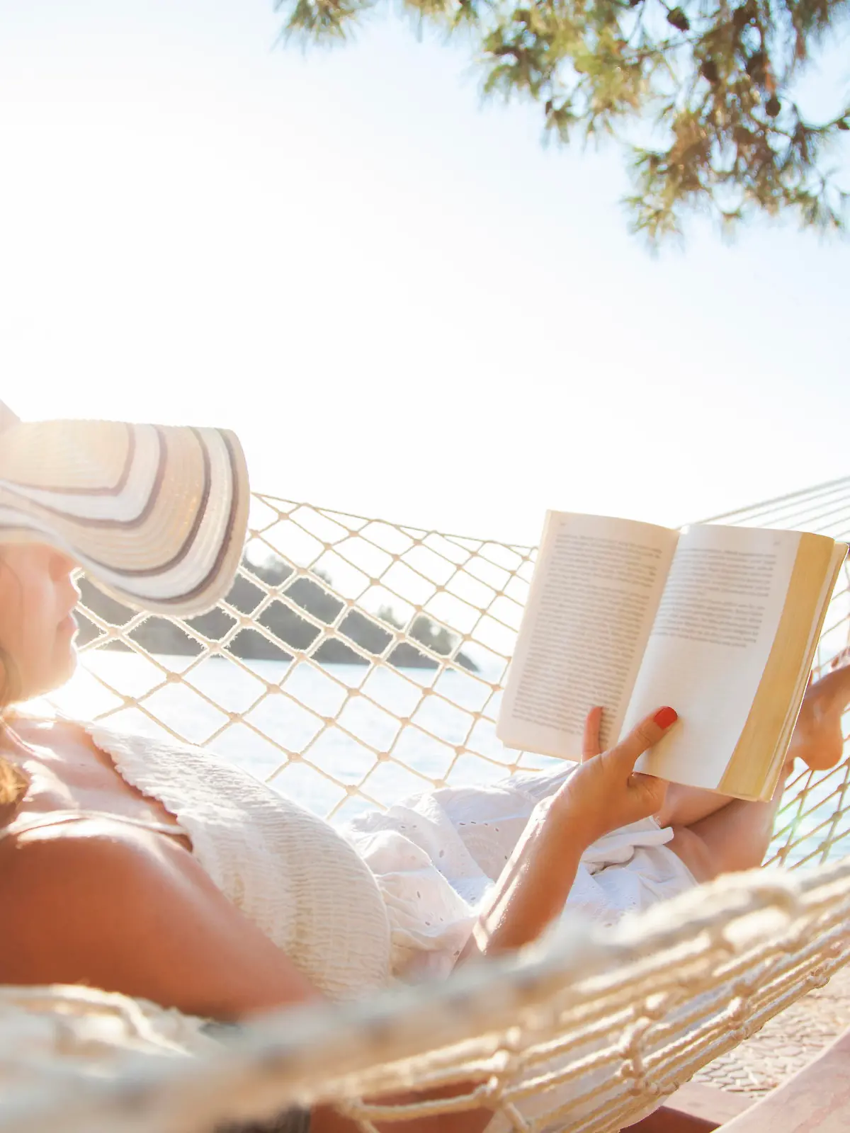 Woman in a hammock with book on summer day