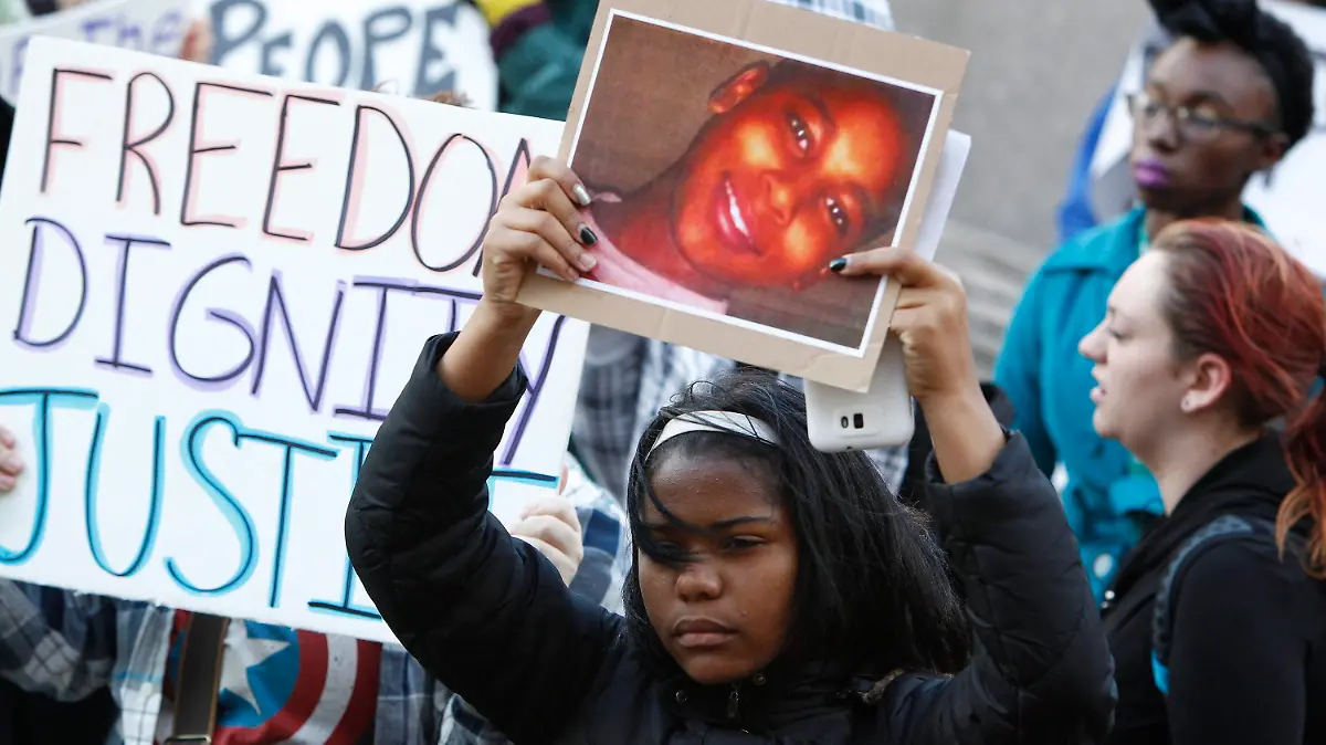 ARCHIV - 24.11.2014, USA, Cleveland: Ein Demonstrant hält bei einer Kundgebung auf dem Public Square ein Plakat mit einem Bild von Tamir Rice. Nach den tödlichen Schüssen auf einen zwölfjährigen schwarzen Jungen in den USA im Jahr 2014 hat das Justizministerium die Untersuchung abgeschlossen und keine Anklage gegen zwei beteiligte Polizisten erhoben. Foto: David Maxwell/EPA/dpa +++ dpa-Bildfunk +++