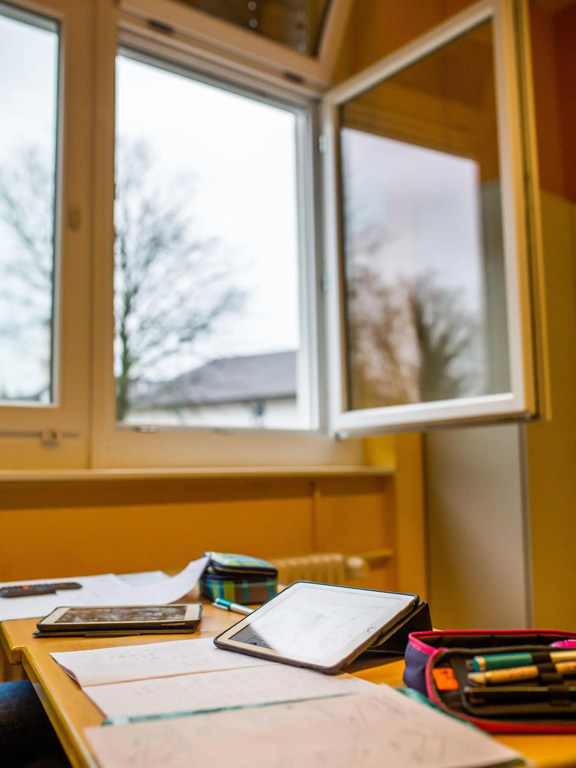 15.12.2020, Baden-Württemberg, Heitersheim: Lernmaterialien liegen auf einem Tisch in einer Schule, während im Hintergrund das geöffnete Fenster des Klassenzimmers zu sehen ist. Die Schulen setzen ab Mittwoch (16.12.2020) den Präsenz-Unterricht aufgrund des Lockdowns aus. Foto: Philipp von Ditfurth/dpa +++ dpa-Bildfunk +++