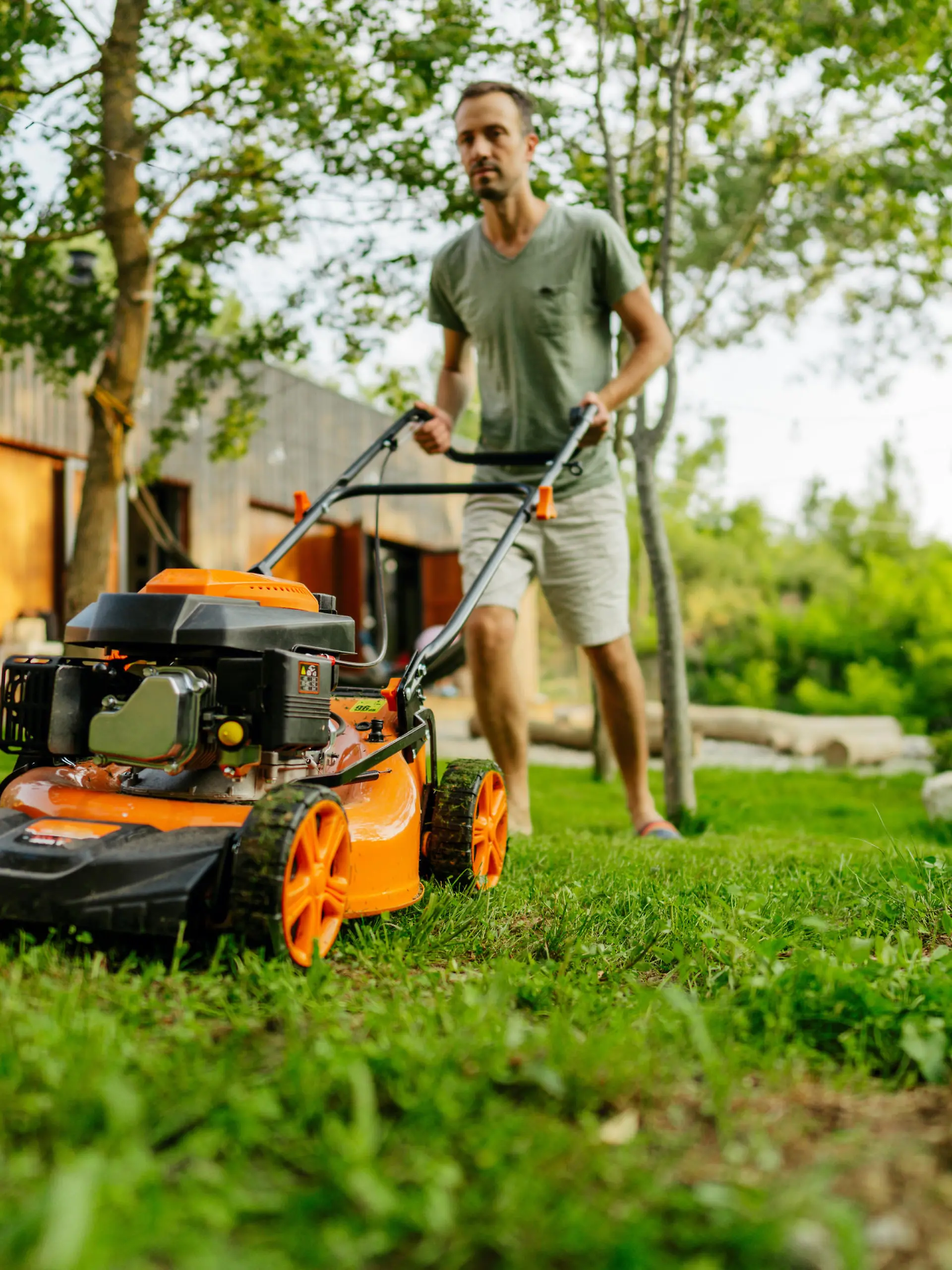 Photo of a young boy helping his father at mowing the lawn in their backyard