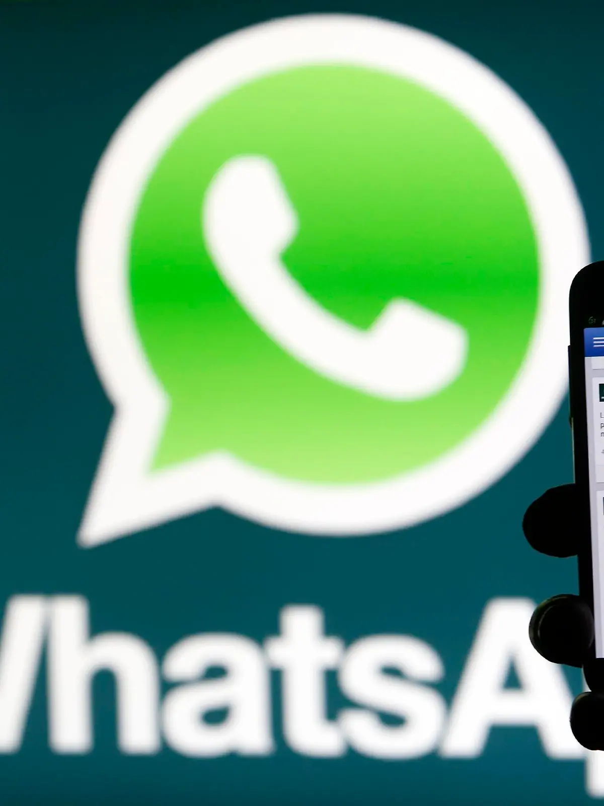 A Whatsapp App logo is seen behind a Samsung Galaxy S4 phone that is logged on to Facebook in the central Bosnian town of Zenica, February 20, 2014. Facebook Inc will buy fast-growing mobile-messaging startup WhatsApp for $19 billion in cash and stock in a landmark deal that places the world's largest social network closer to the heart of mobile communications and may bring younger users into the fold. REUTERS/Dado Ruvic (BOSNIA AND HERZEGOVINA - Tags: BUSINESS)