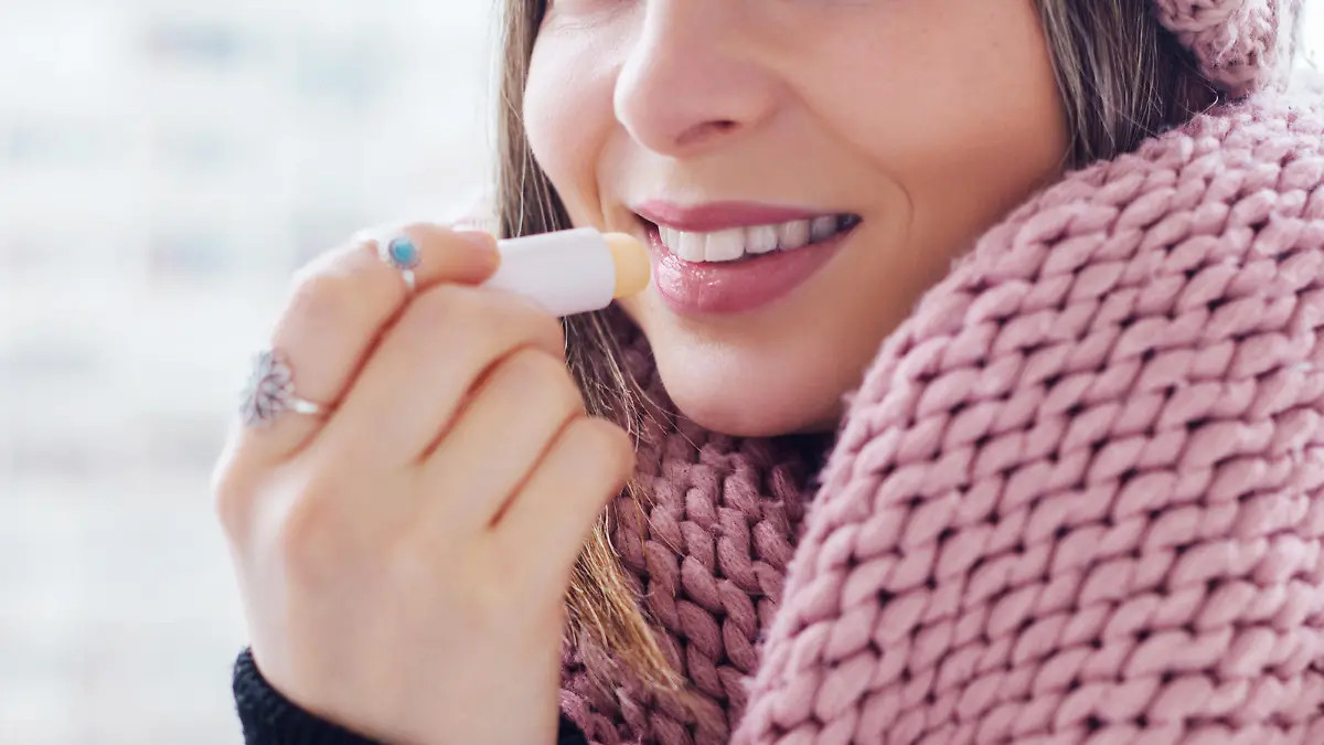 Young women apply lip care balm outside, on cold weather