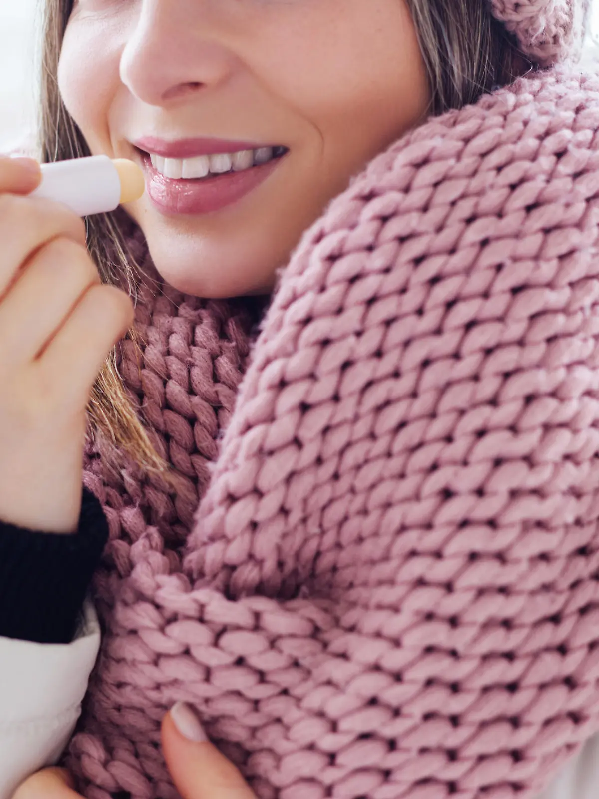Young women apply lip care balm outside, on cold weather