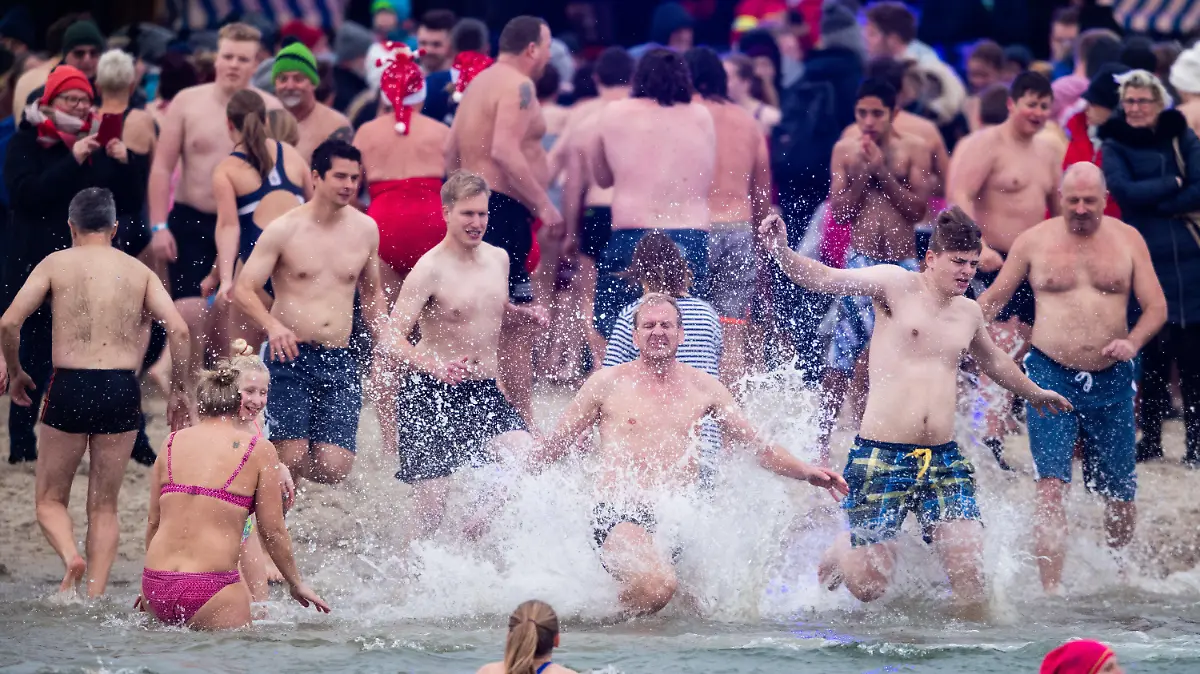 ARCHIV - 01.01.2019, Niedersachsen, Butjadingen: Schwimmer laufen beim traditionellen Anbaden am Neujahrstag vor der Nordseelagune in Butjadingen ins Wasser. (zu dpa: «Inseln haken Jahreswechsel-Geschäft ab - Hoffen auf Oster-Urlauber») Foto: Mohssen Assanimoghaddam/dpa +++ dpa-Bildfunk +++